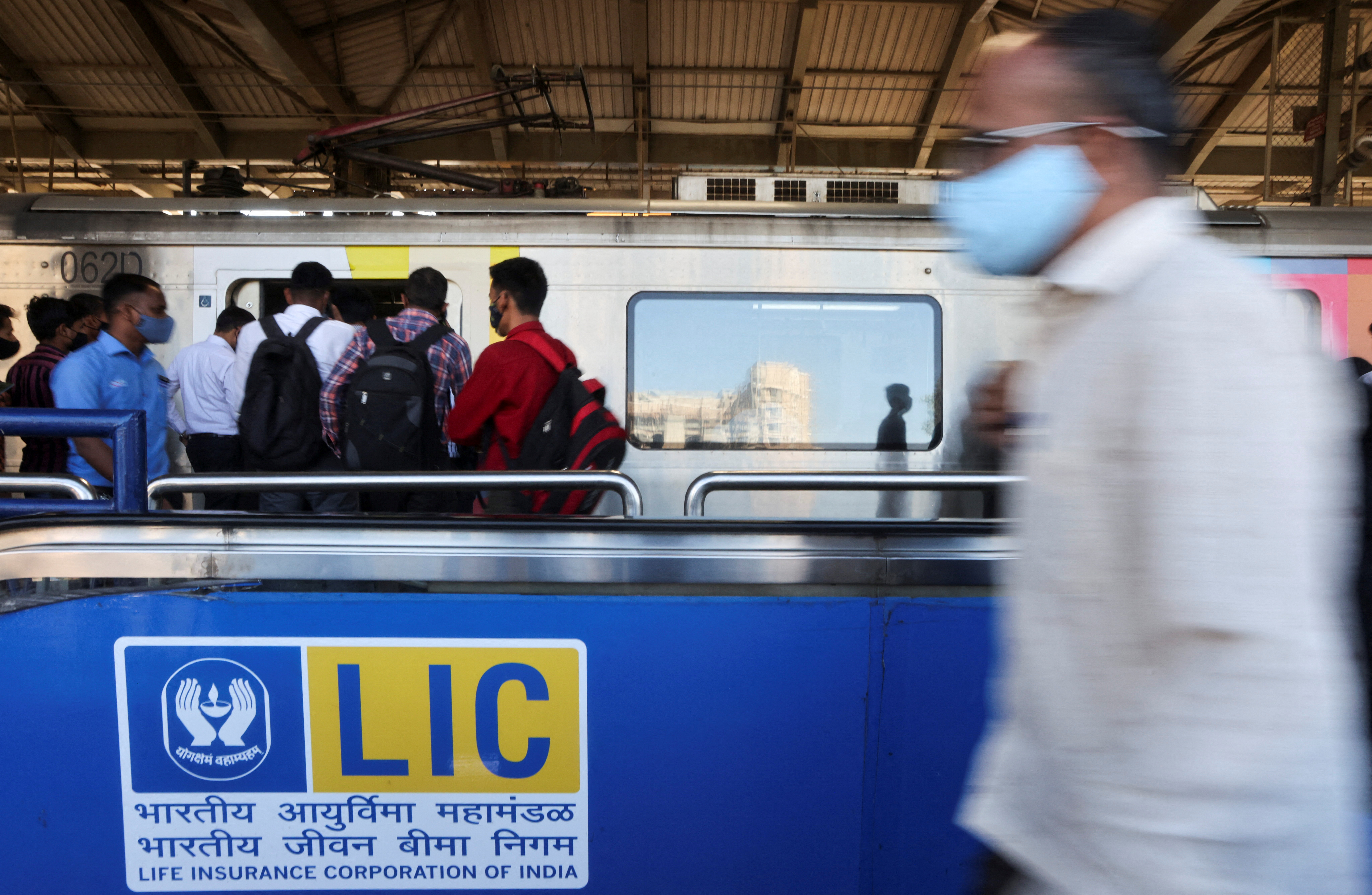 A man walks past a Life Insurance Corporation of India (LIC) logo at a metro station in Mumbai