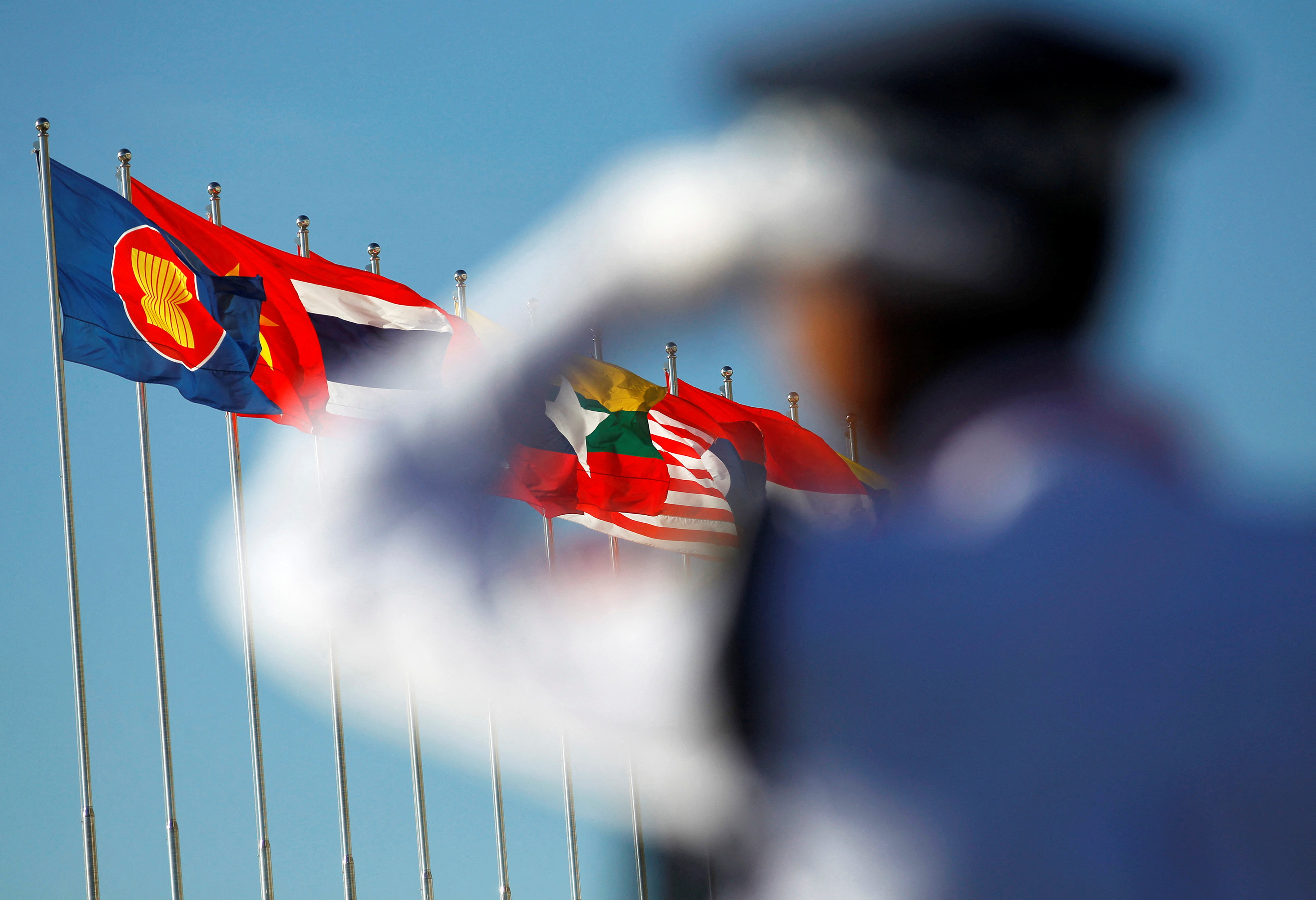 A police officer stands near national flags of ASEAN counties flags during 25th ASEAN Summit in Myanmar International Convention Centre in Naypyitaw
