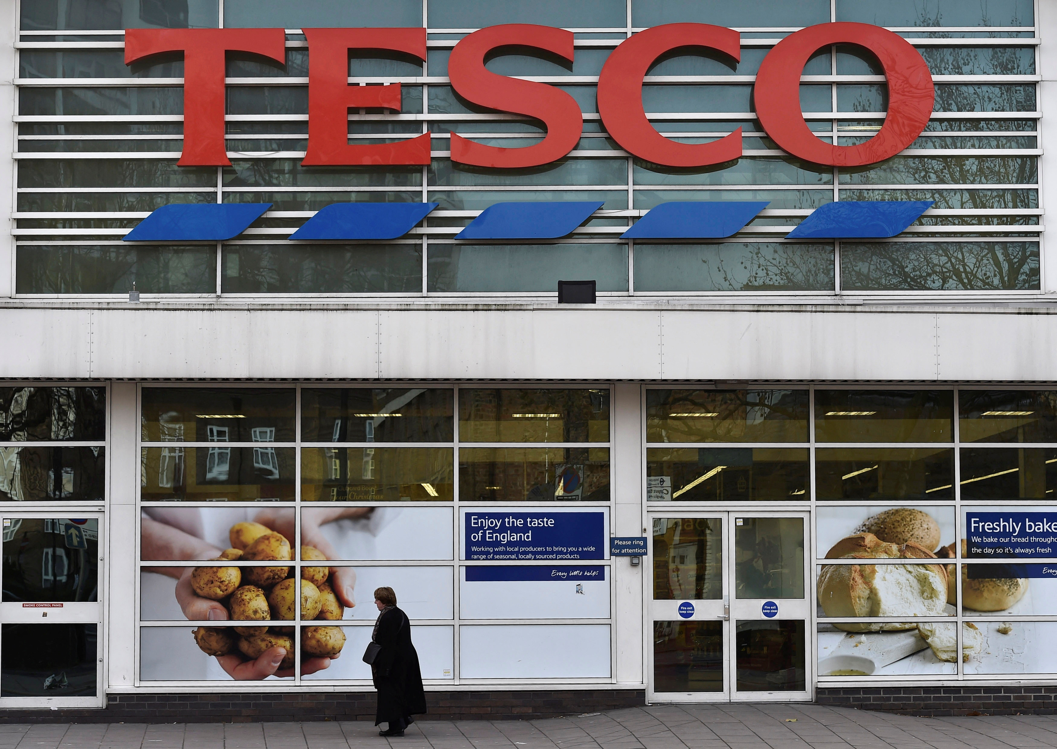 Woman walks past a Tesco supermarket in central London