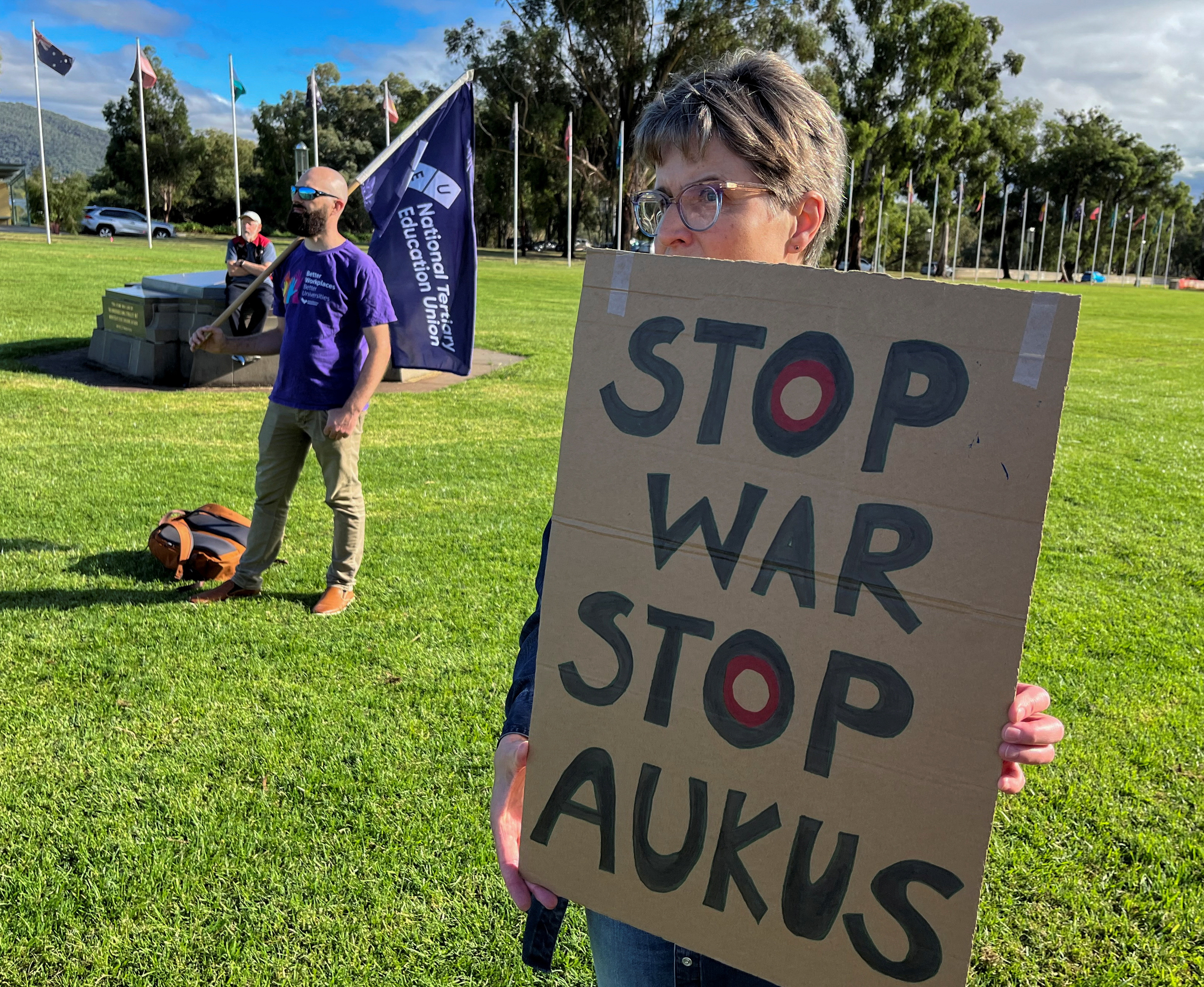 Anti-AUKUS protesters stand outside Australia’s parliament, in Canberra