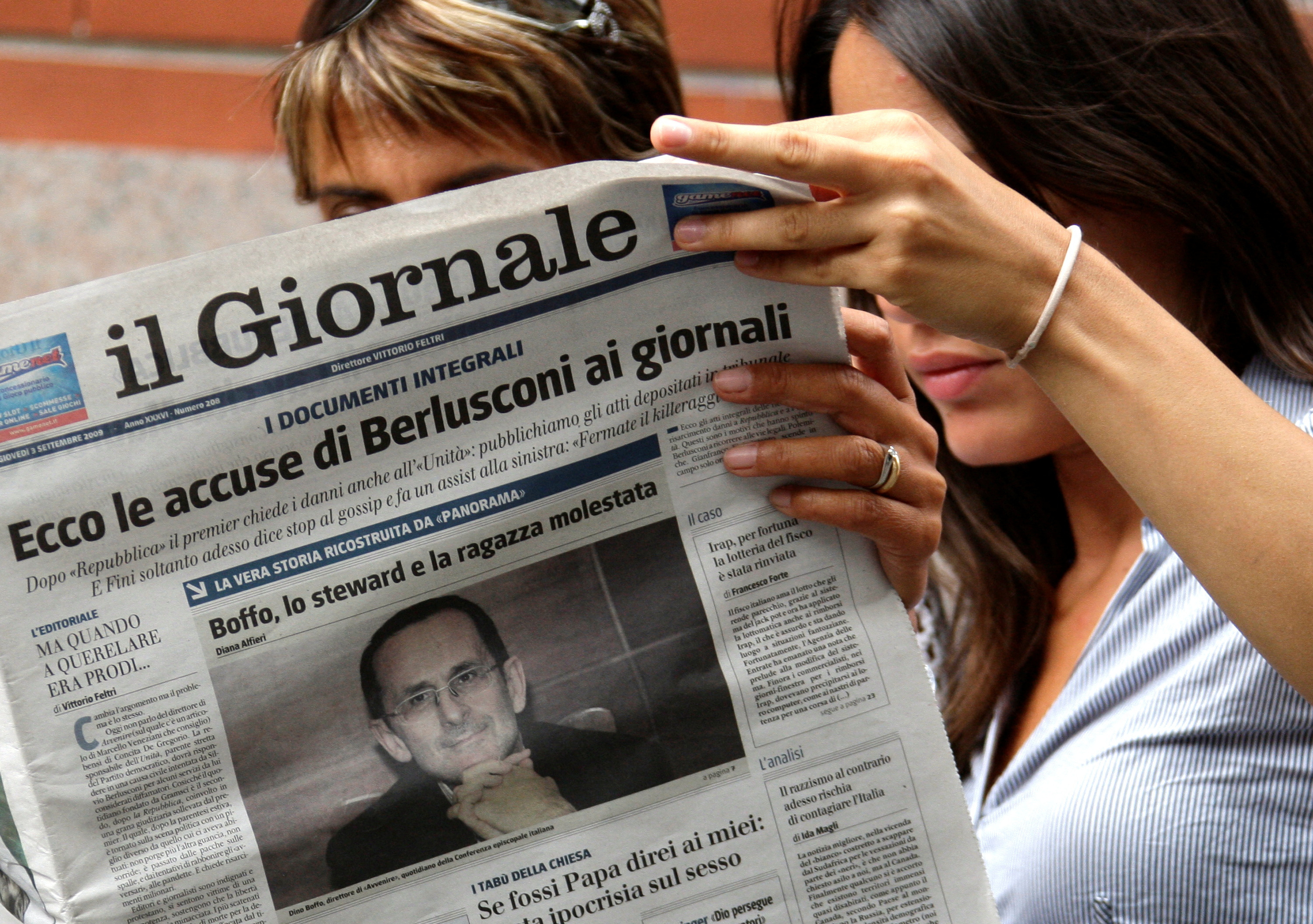 Two women read Il Giornale with picture of Boffo, editor of Avvenire, on its front page in downtown Milan