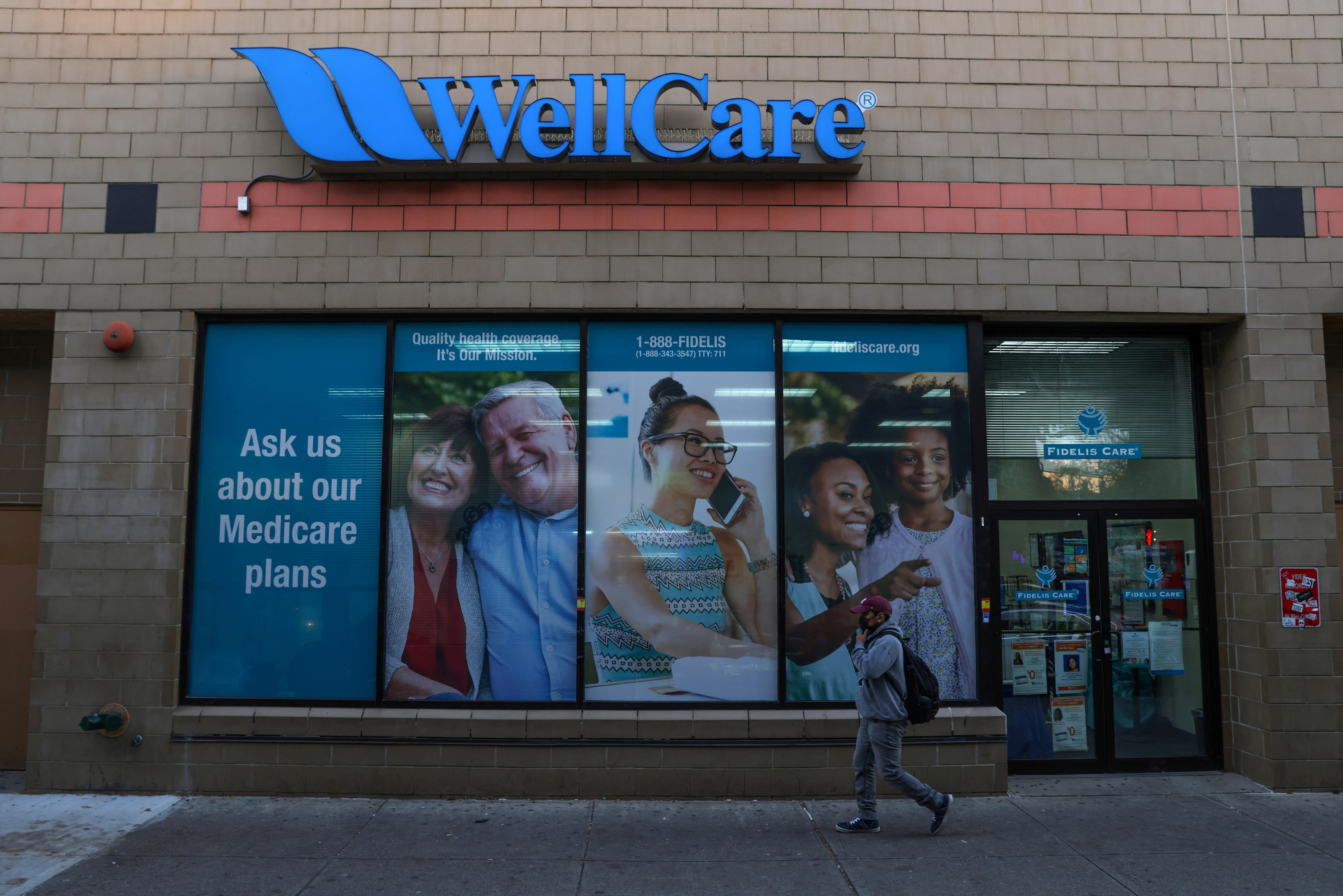 A person walks by a Wellcare and Fidelis Care location, part of the Centene Corporation, in Queens, New York