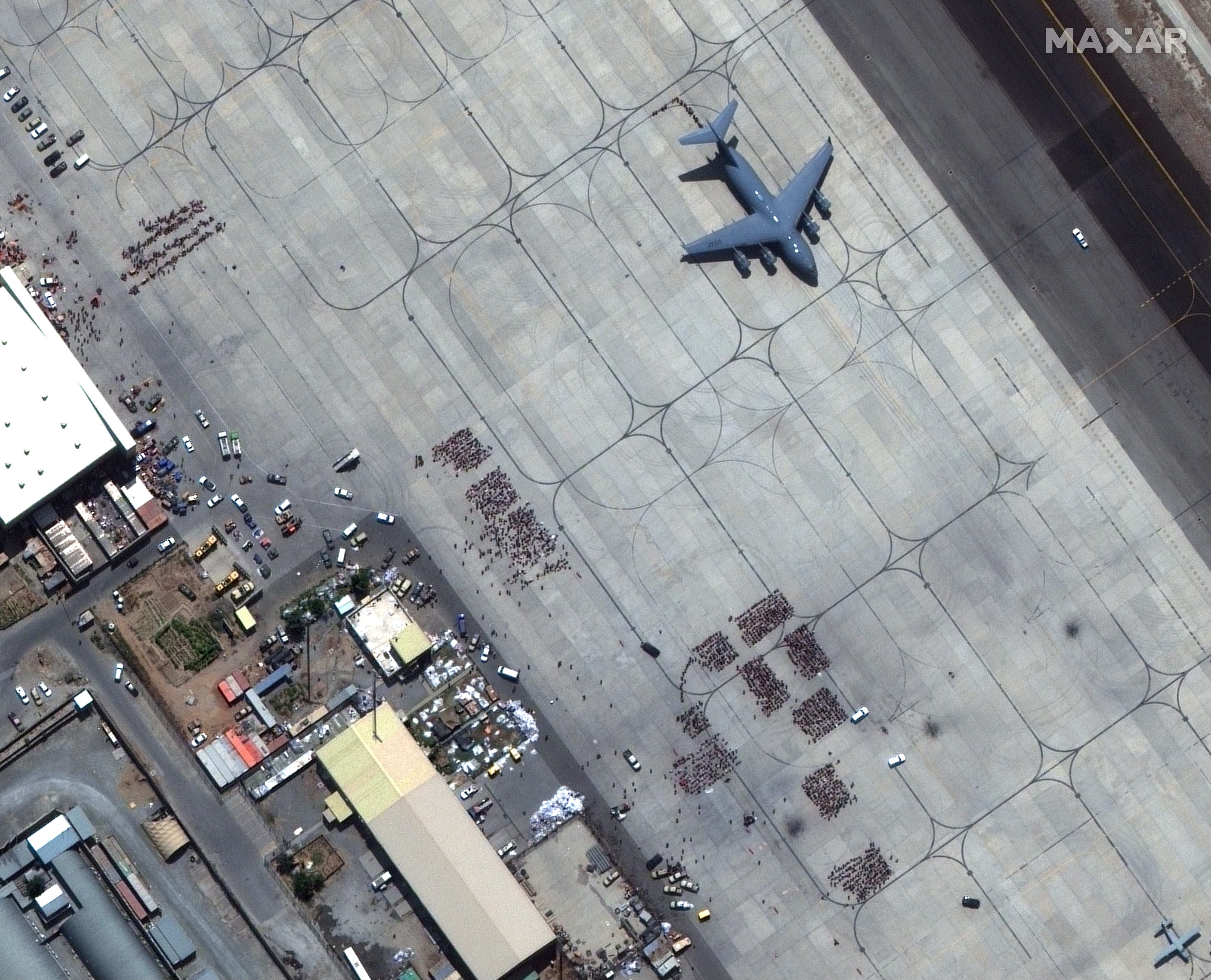 Groups of people wait on tarmac at Kabul's airport, Afghanistan August 23, 2021. SATELLITE IMAGE 2021 MAXAR TECHNOLOGIES/Handout via REUTERS