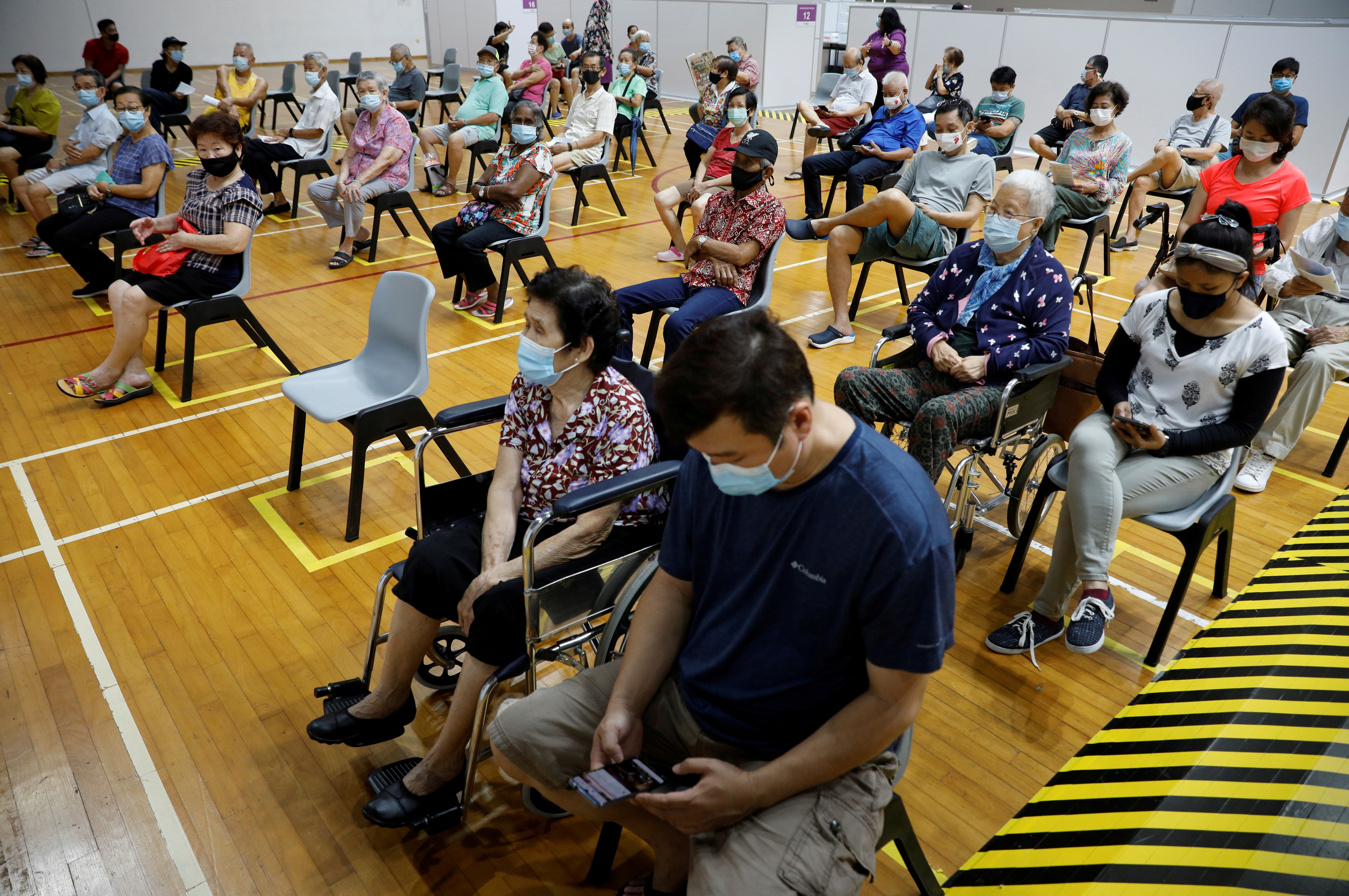 People wait at an observation area after their vaccination at a coronavirus disease (COVID-19) vaccination center in Singapore