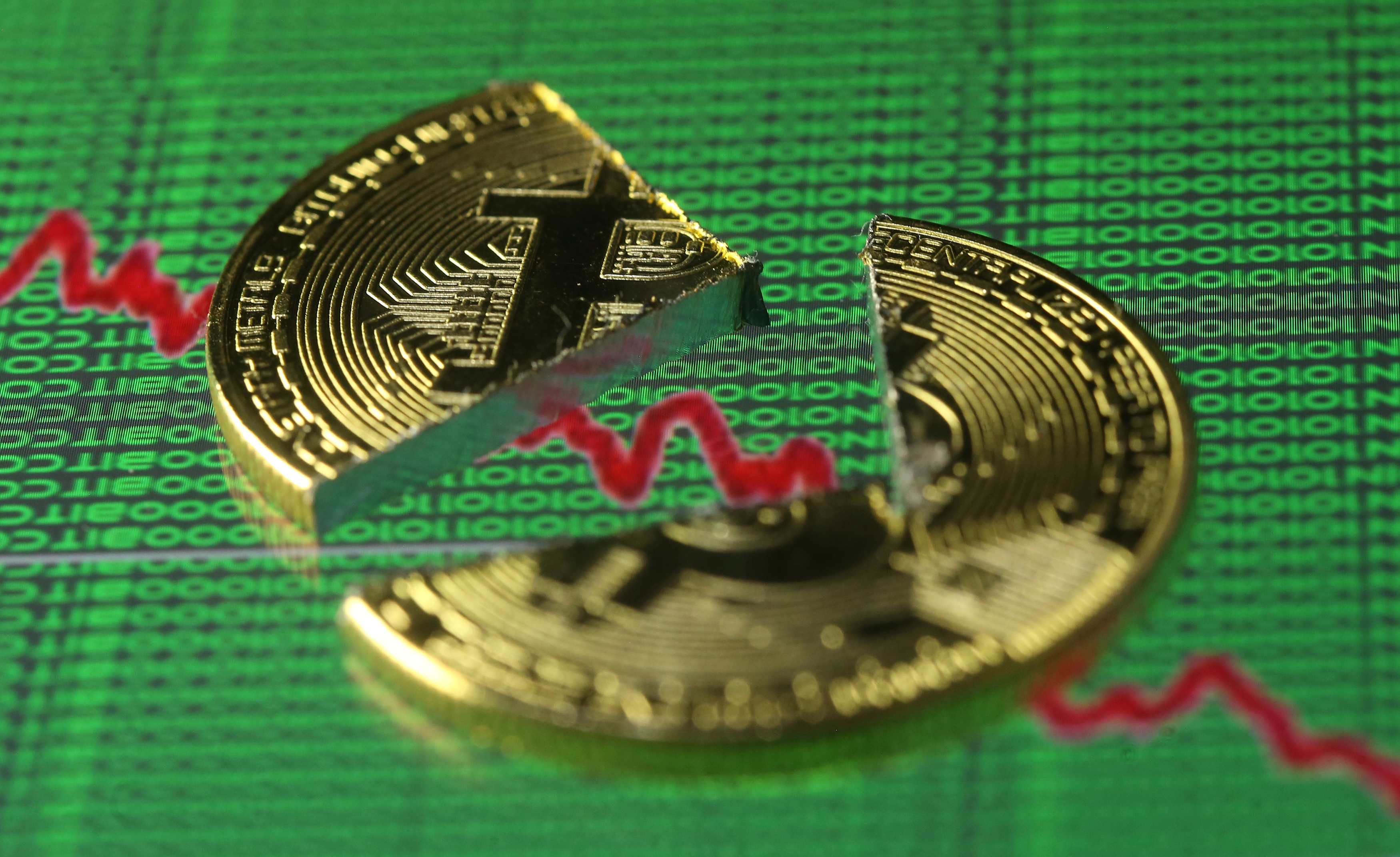 Broken representation of the Bitcoin virtual currency, placed on a monitor that displays stock graph and binary codes, are seen in this illustration picture, December 21, 2017.