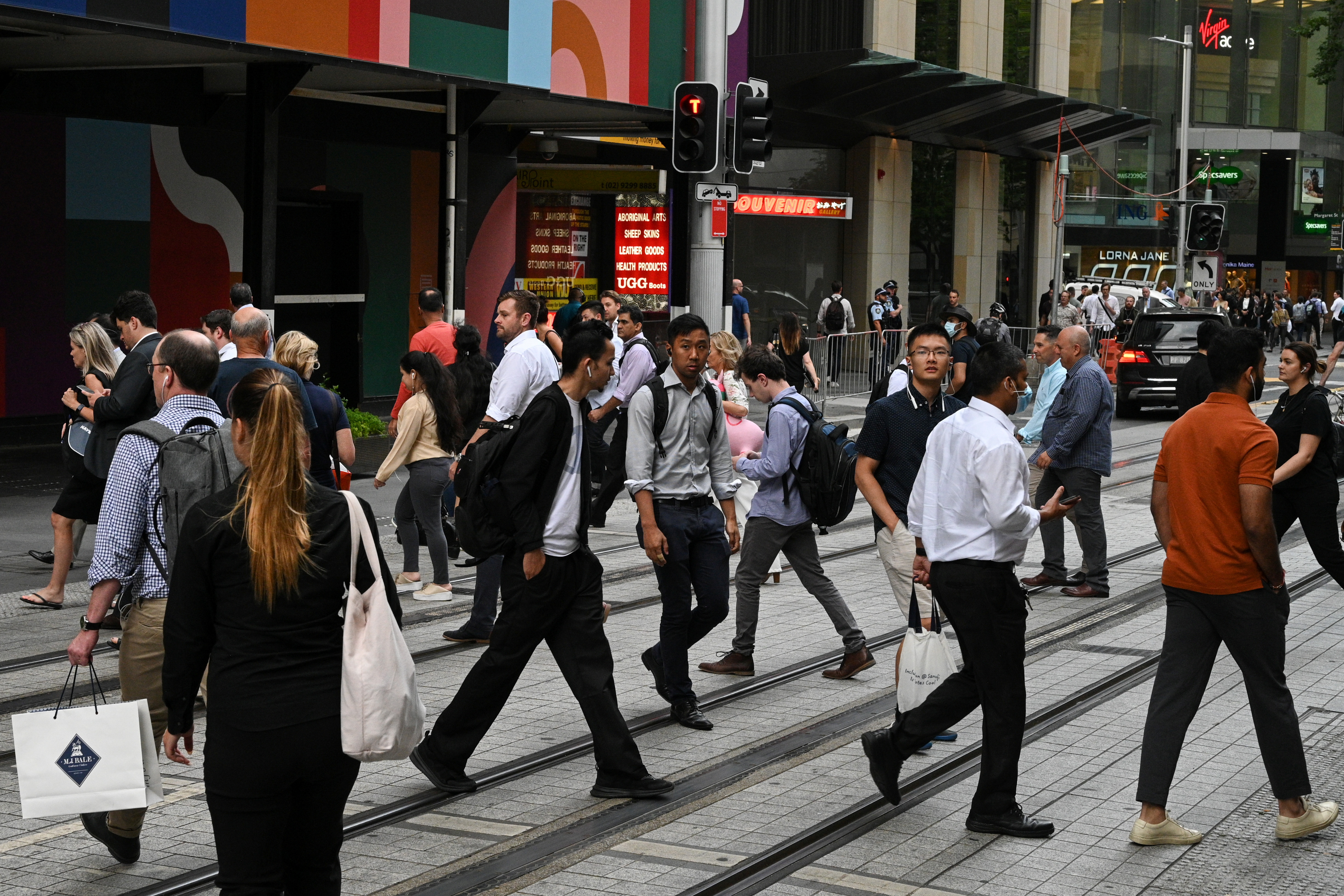 As pessoas atravessam uma rua no centro da cidade de Sydney