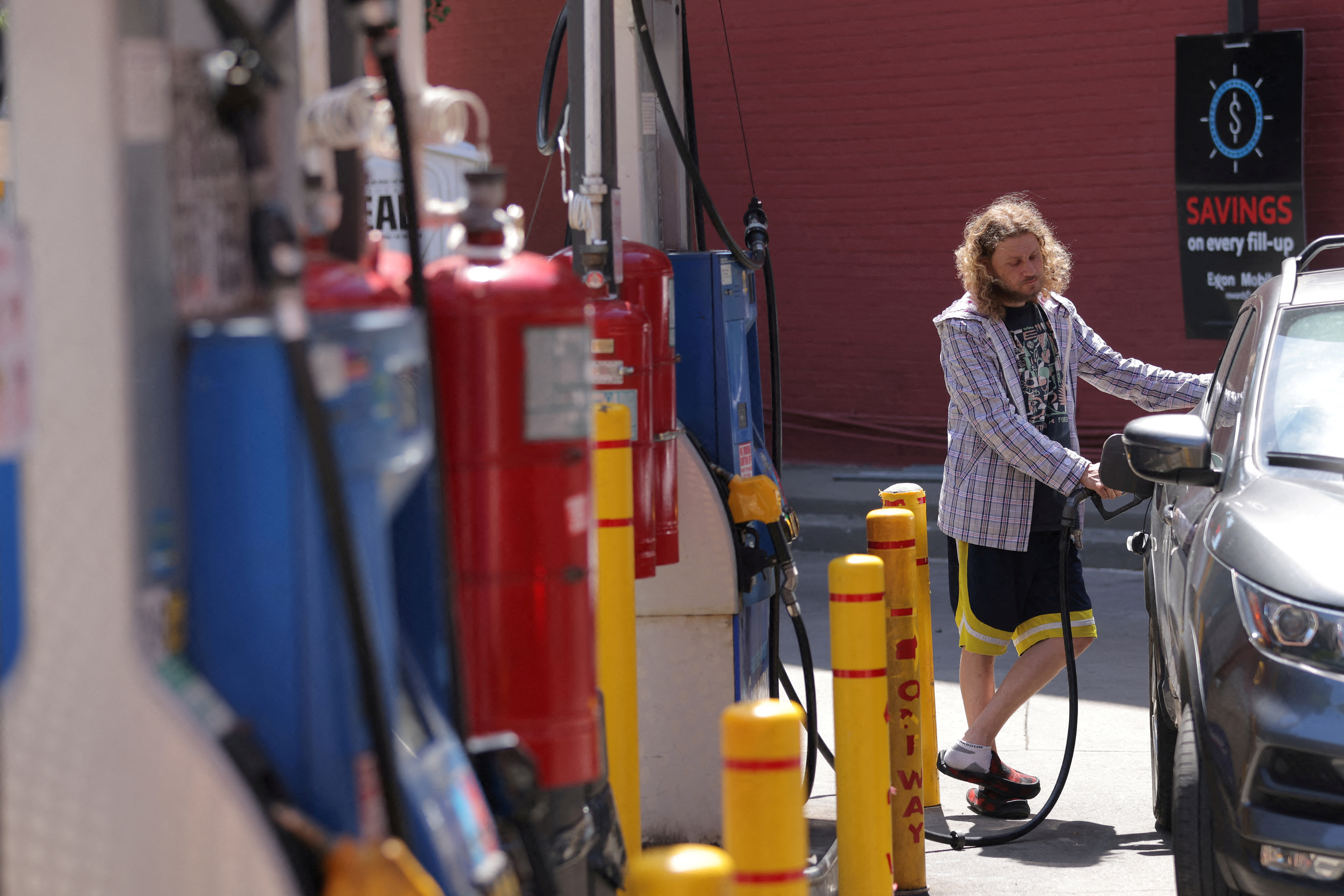 A person puts gas in a vehicle at a gas station in Manhattan, New York City