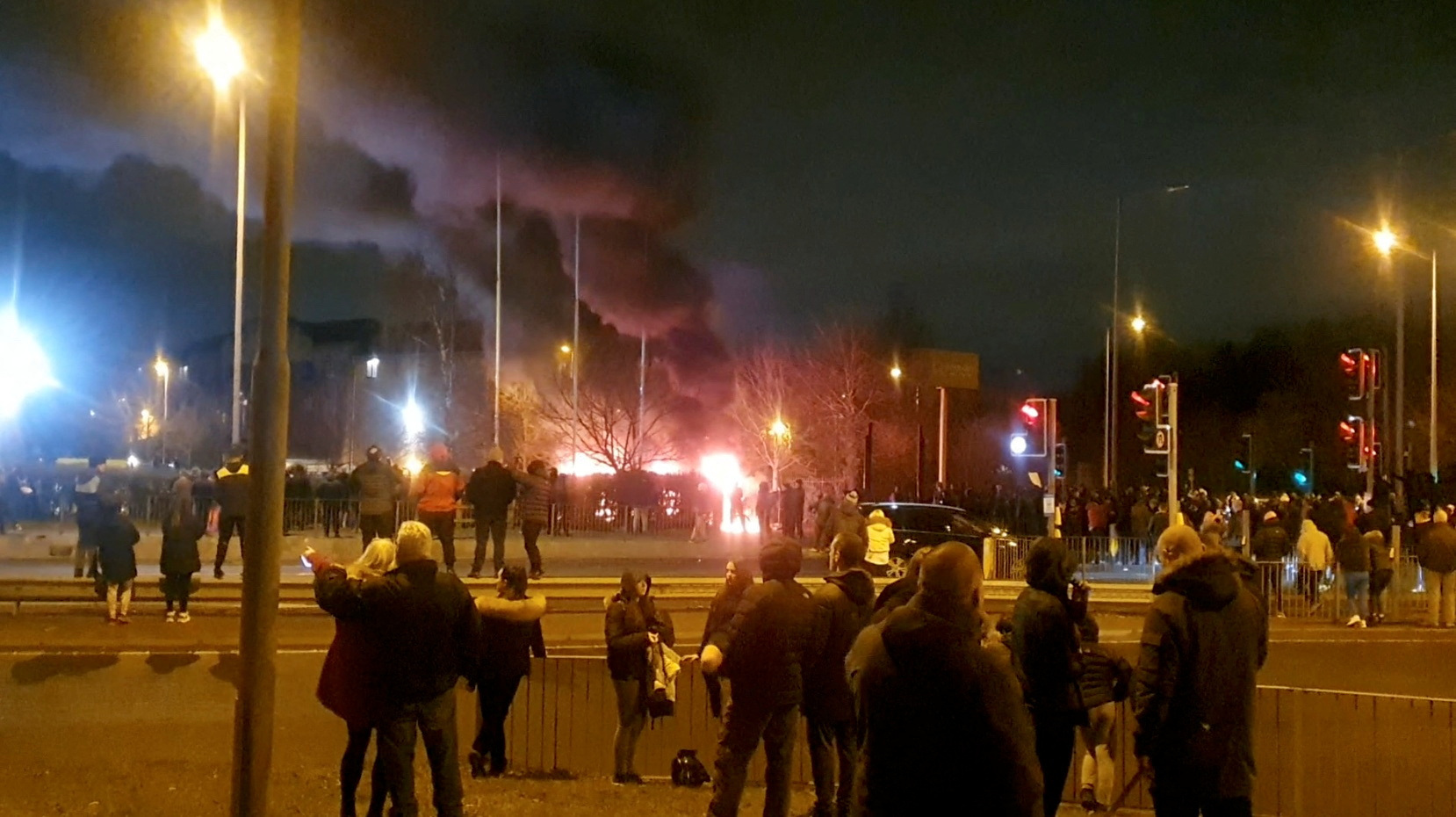 People look at a fire outside a hotel providing refuge to asylum seekers following a protest in Knowsley