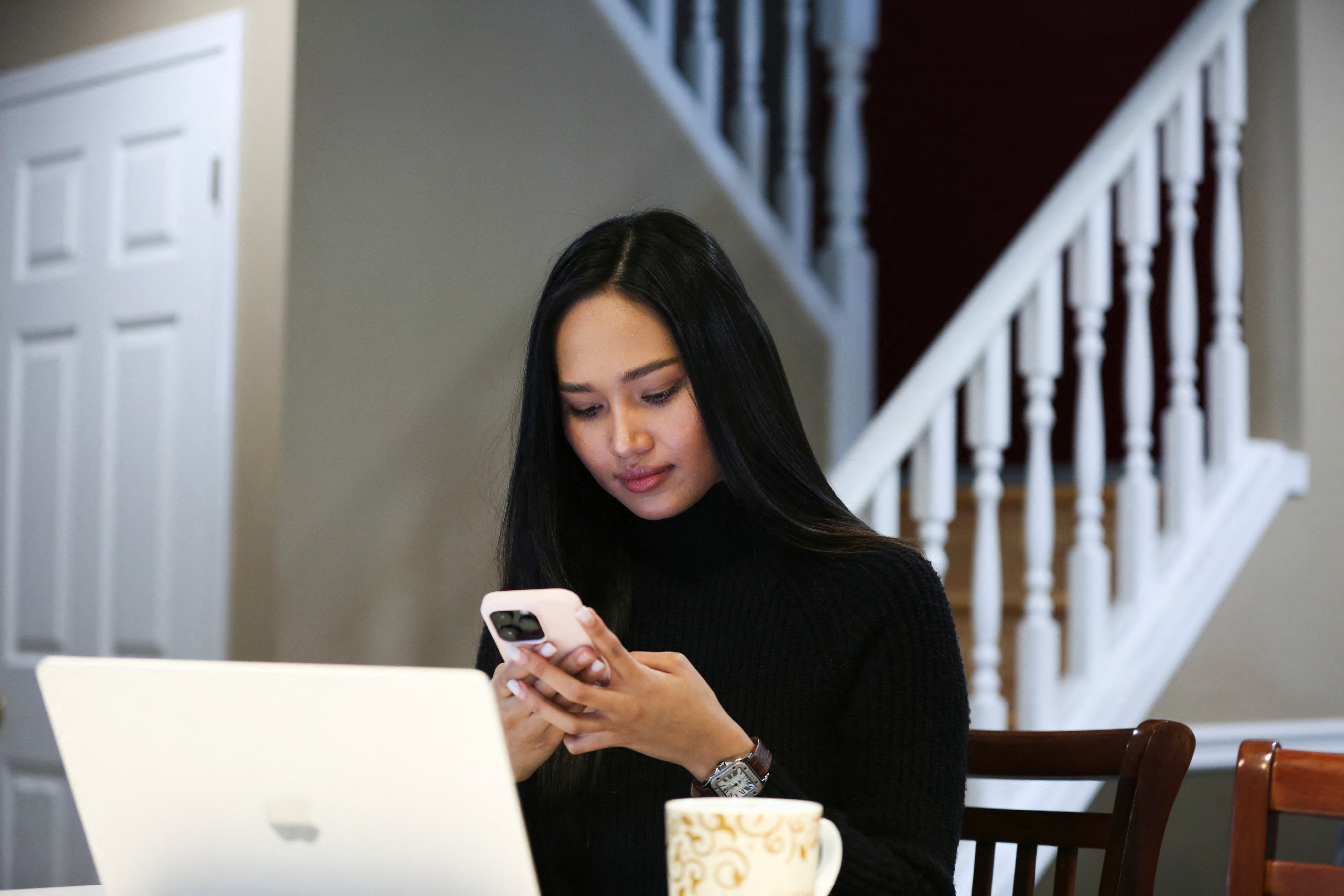 Myanmar's beauty queen Han Lay, who had been exiled after speaking out against military rule in her country, uses her phone while working at her house in London