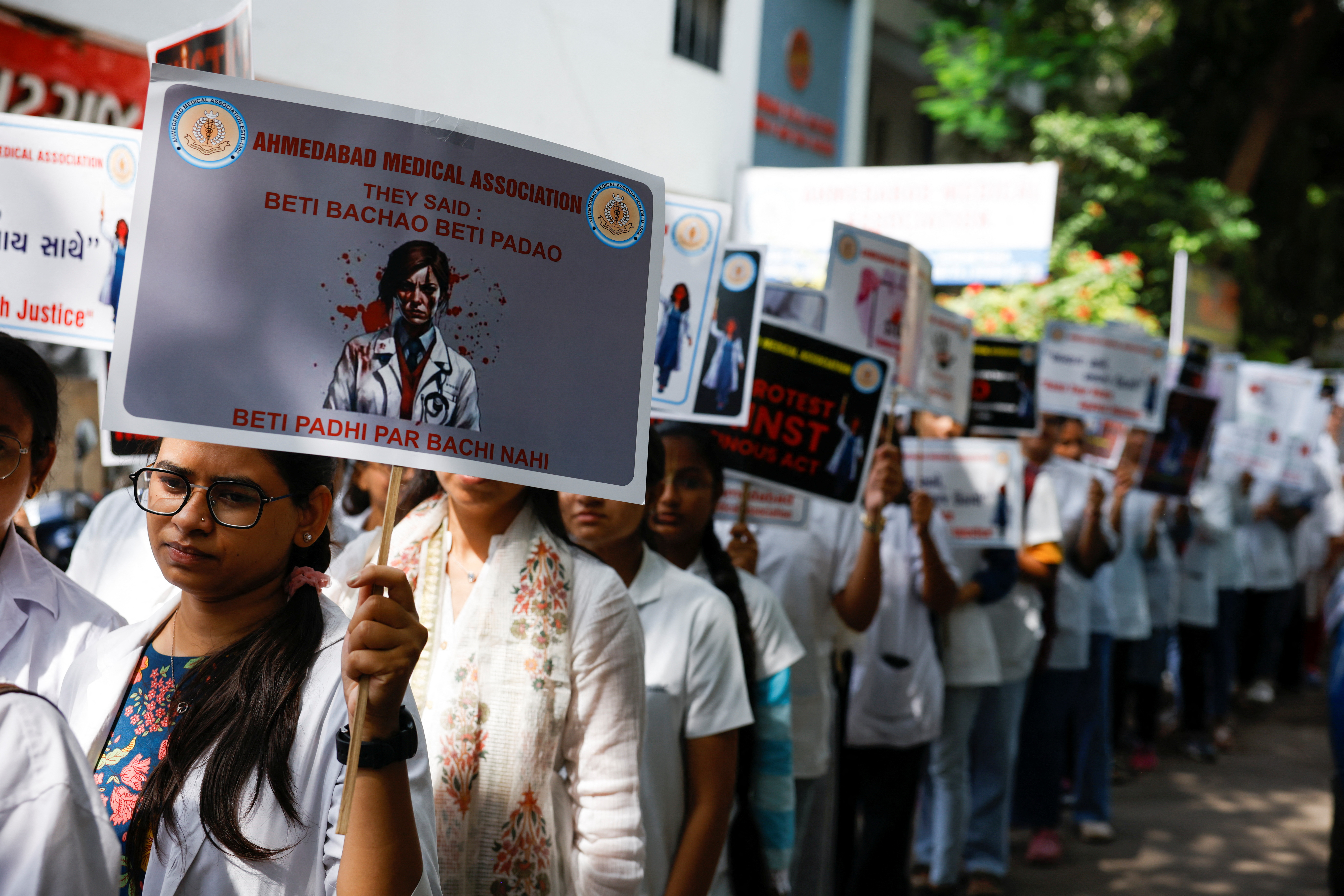 Resident doctors hold posters and shout slogans during a protest march, in Ahmedabad