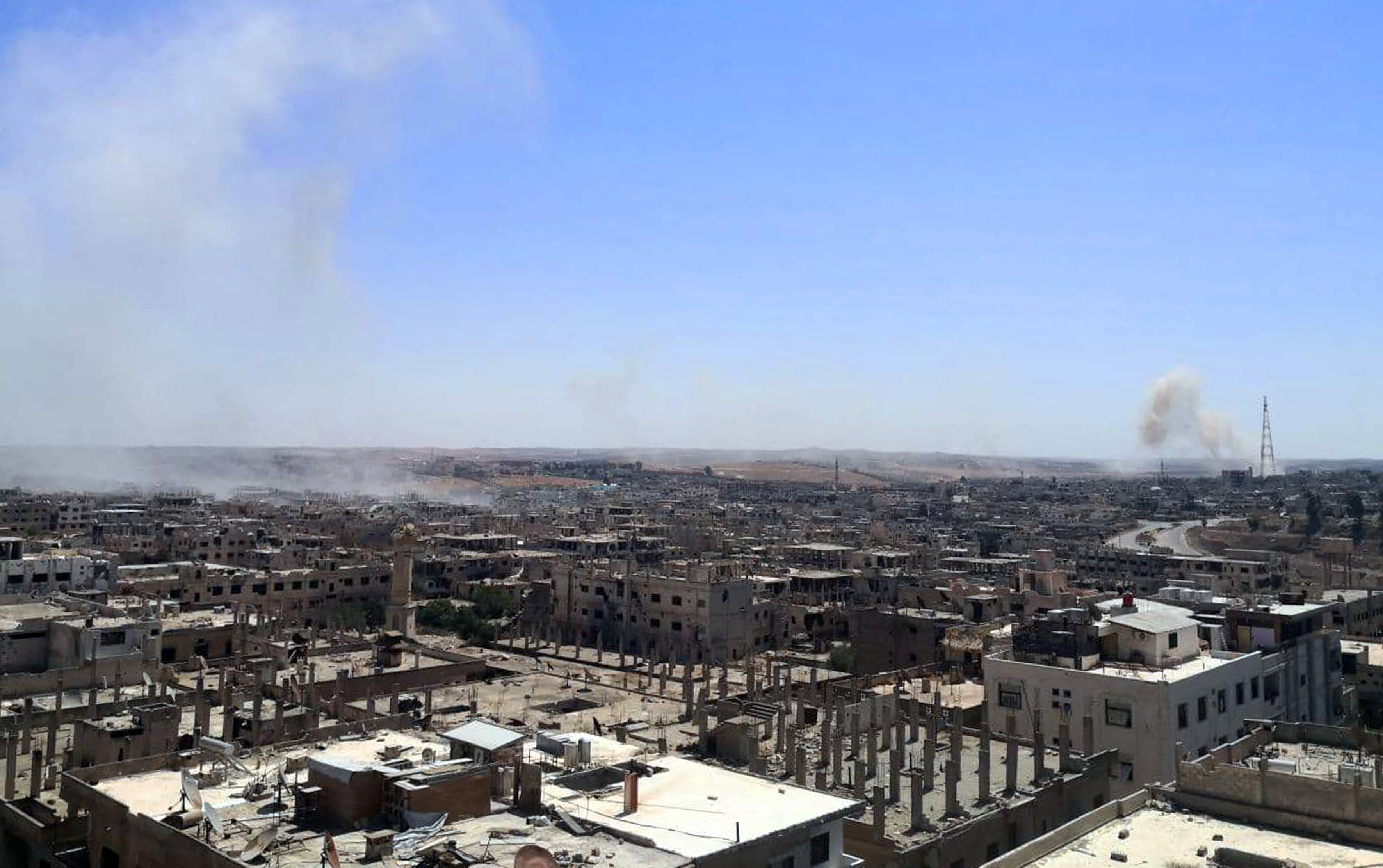 A view shows damaged buildings as smoke rises in Deraa