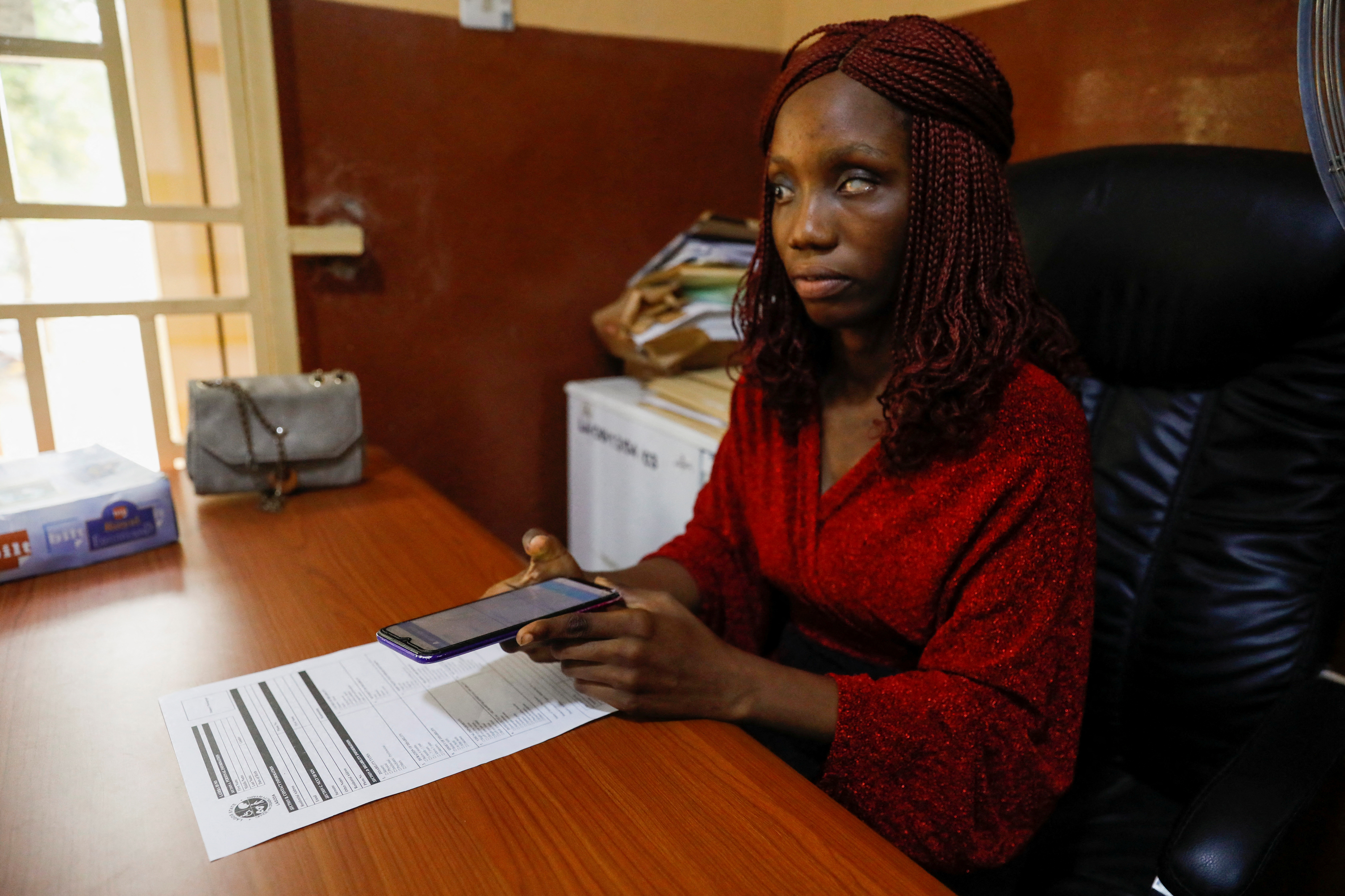 Balogun Mary, 25, a visually impaired Nigerian Youth Corps Member, uses Visis application to read a document at an office in Lagos