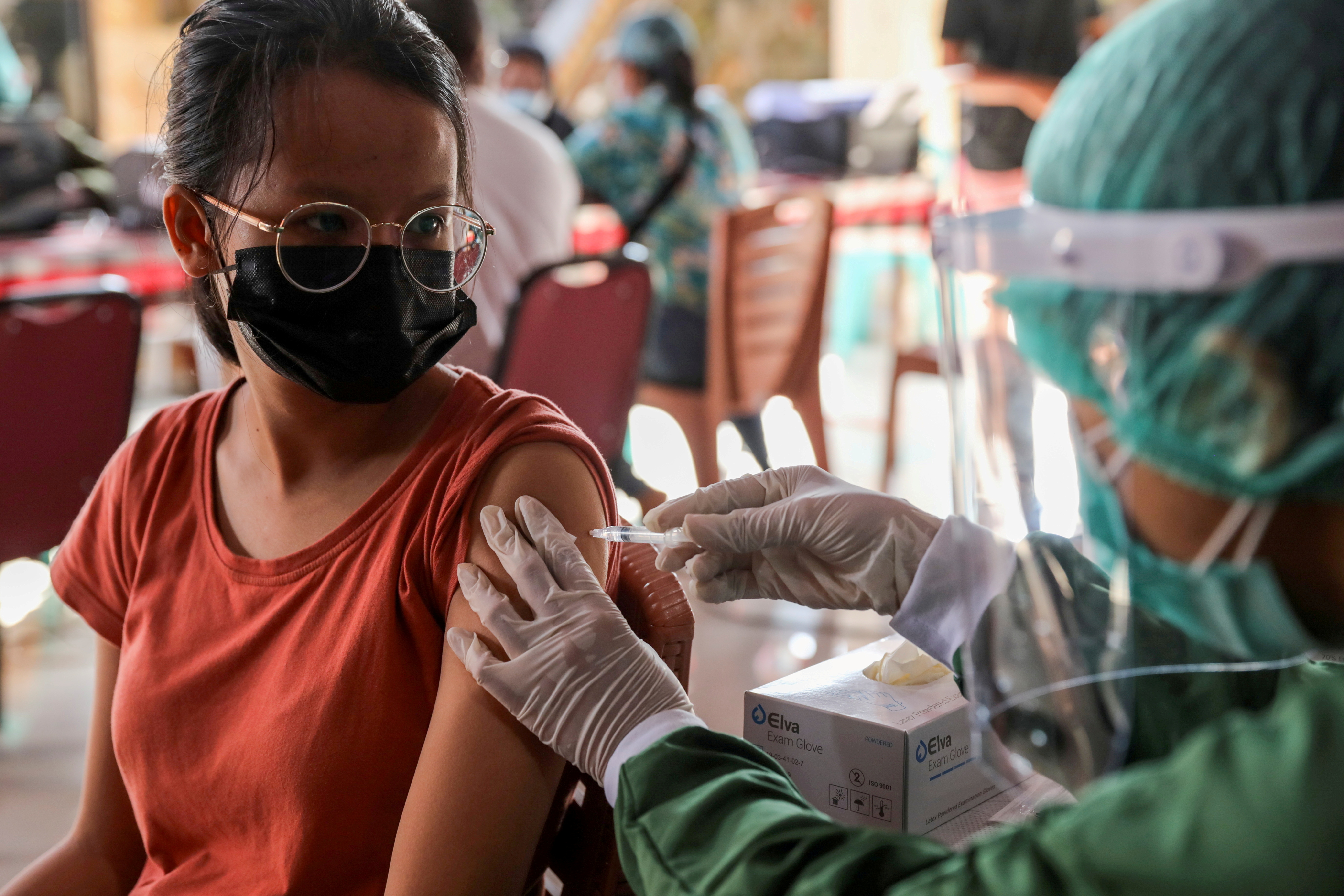 A woman receives a dose of AstraZeneca COVID-19 vaccine during a mass vaccination programme for Green Zone Tourism in Sanur, Bali, Indonesia,