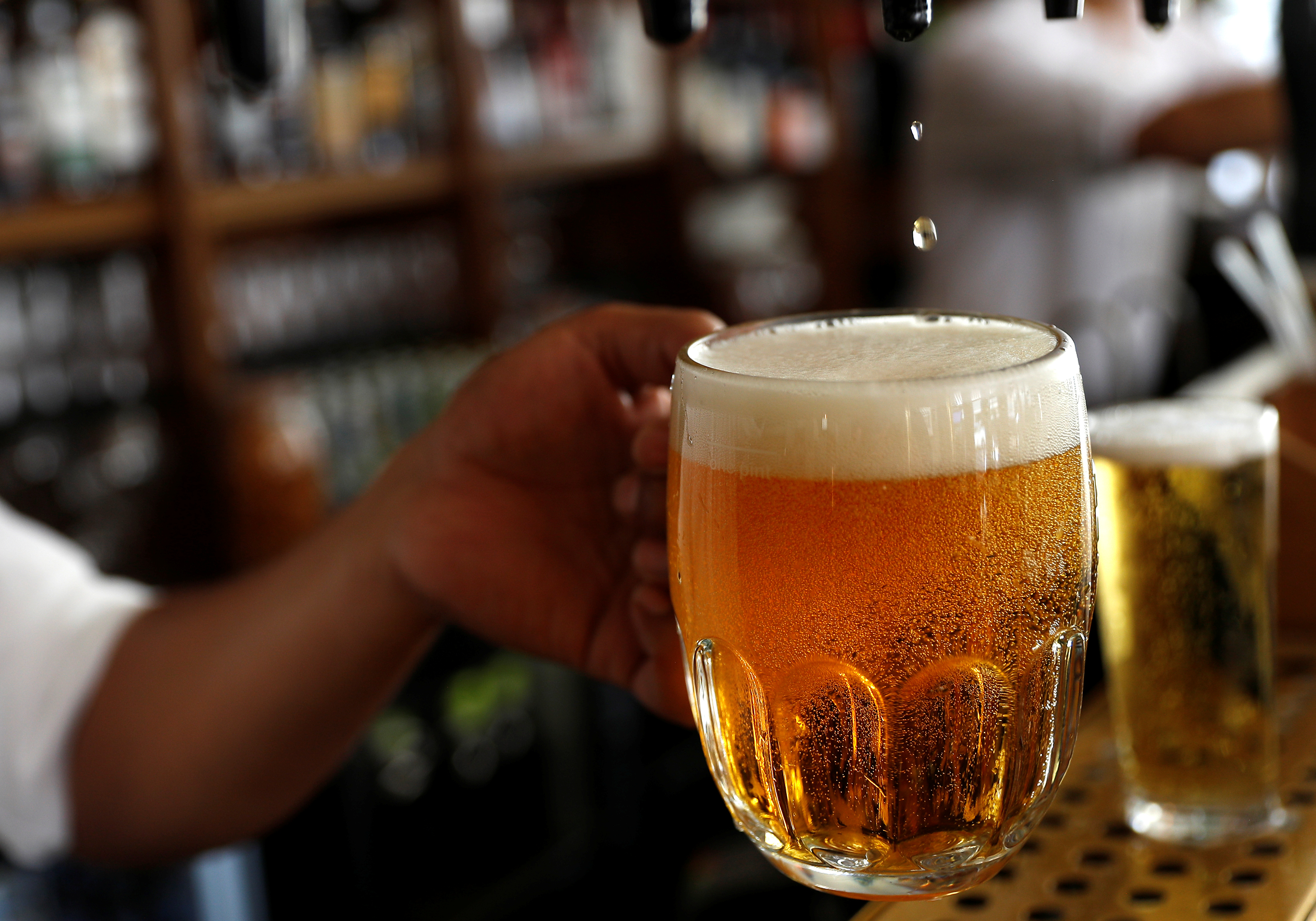A pint of beer is poured into a glass in a bar in London