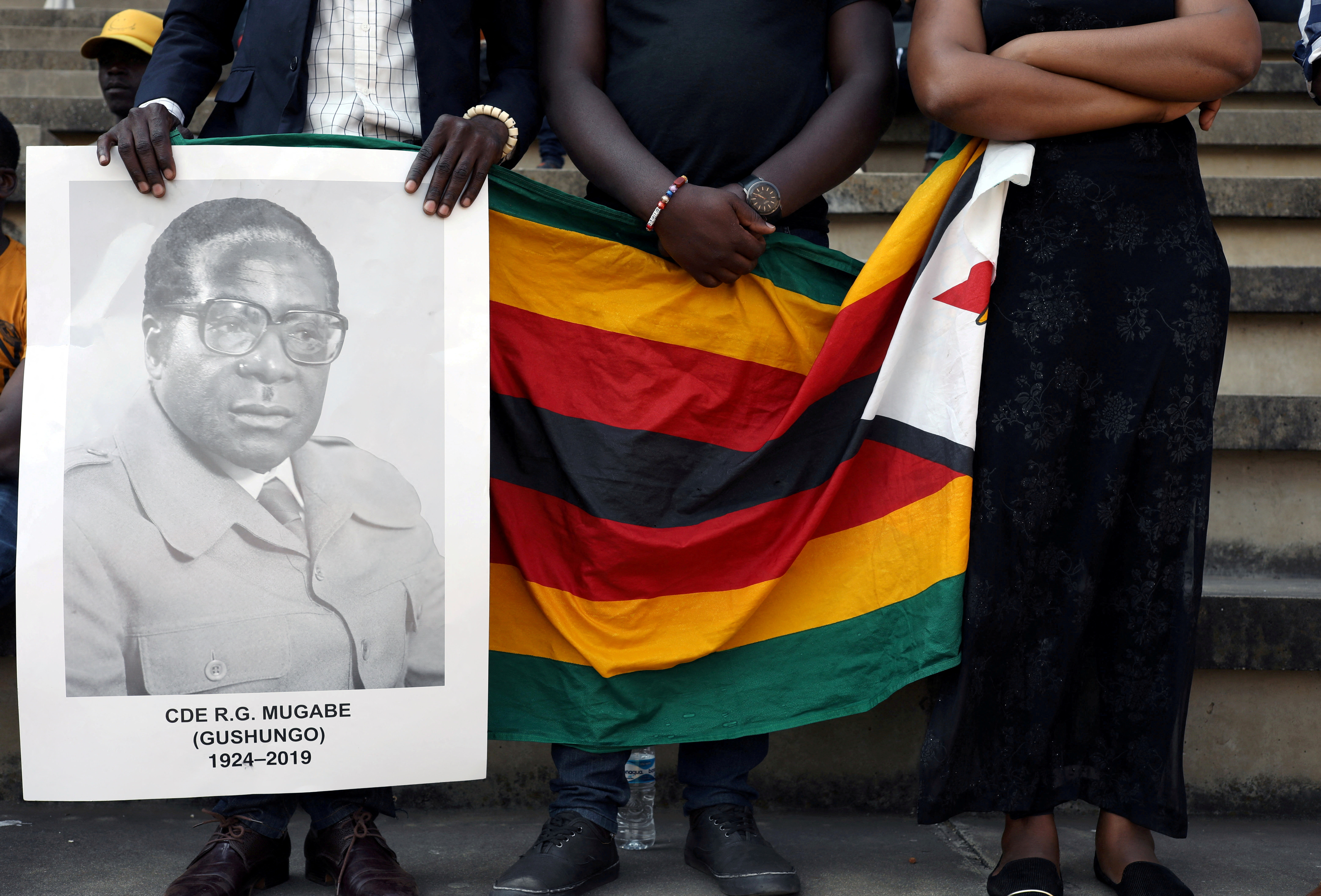 Mourners hold a poster during the state funeral of Zimbabwe's longtime ruler Robert Mugabe at a national sports stadium in Harare