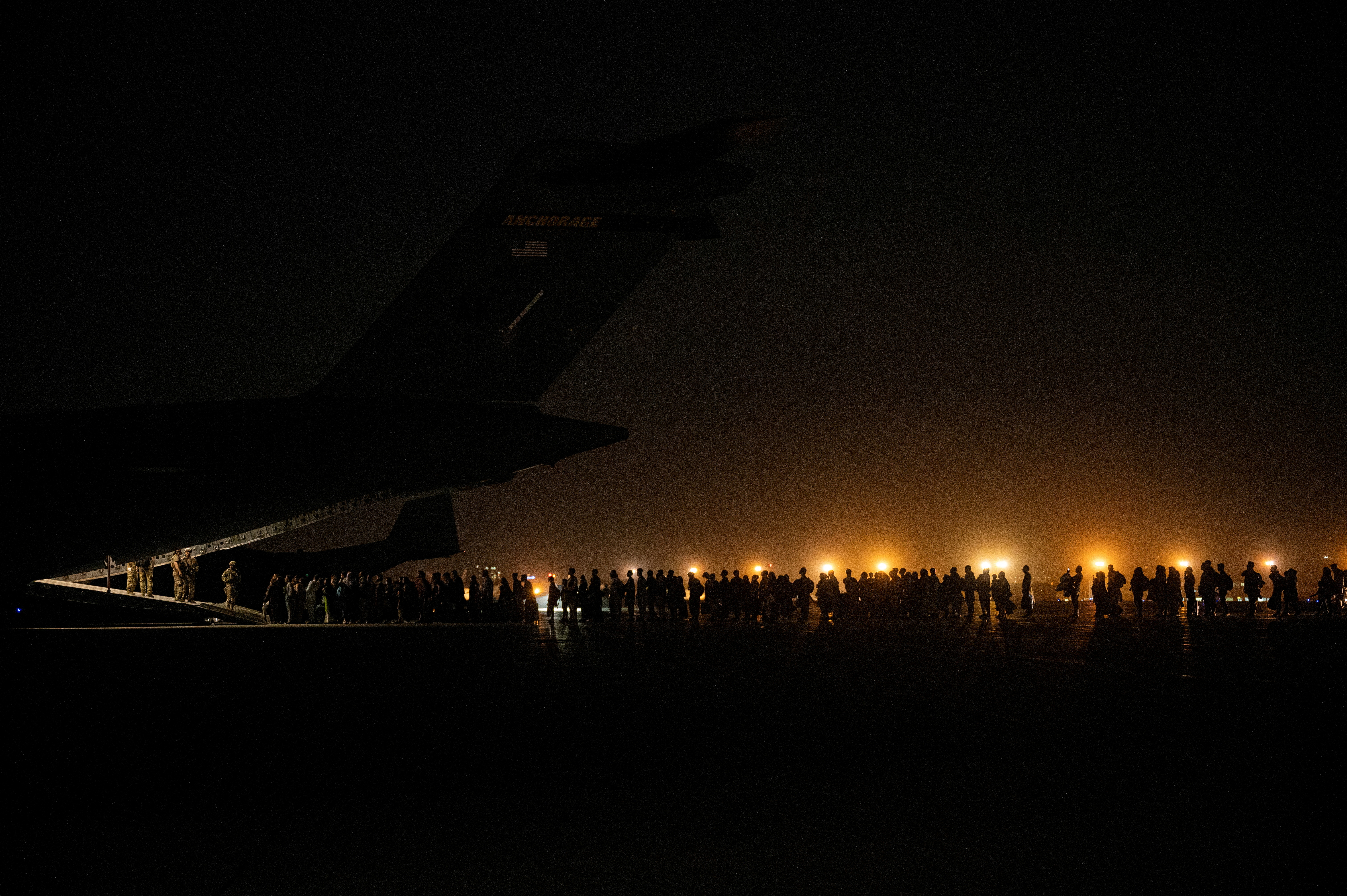 Evacuees from Afghanistan board a military aircraft during an evacuation from Kabul
