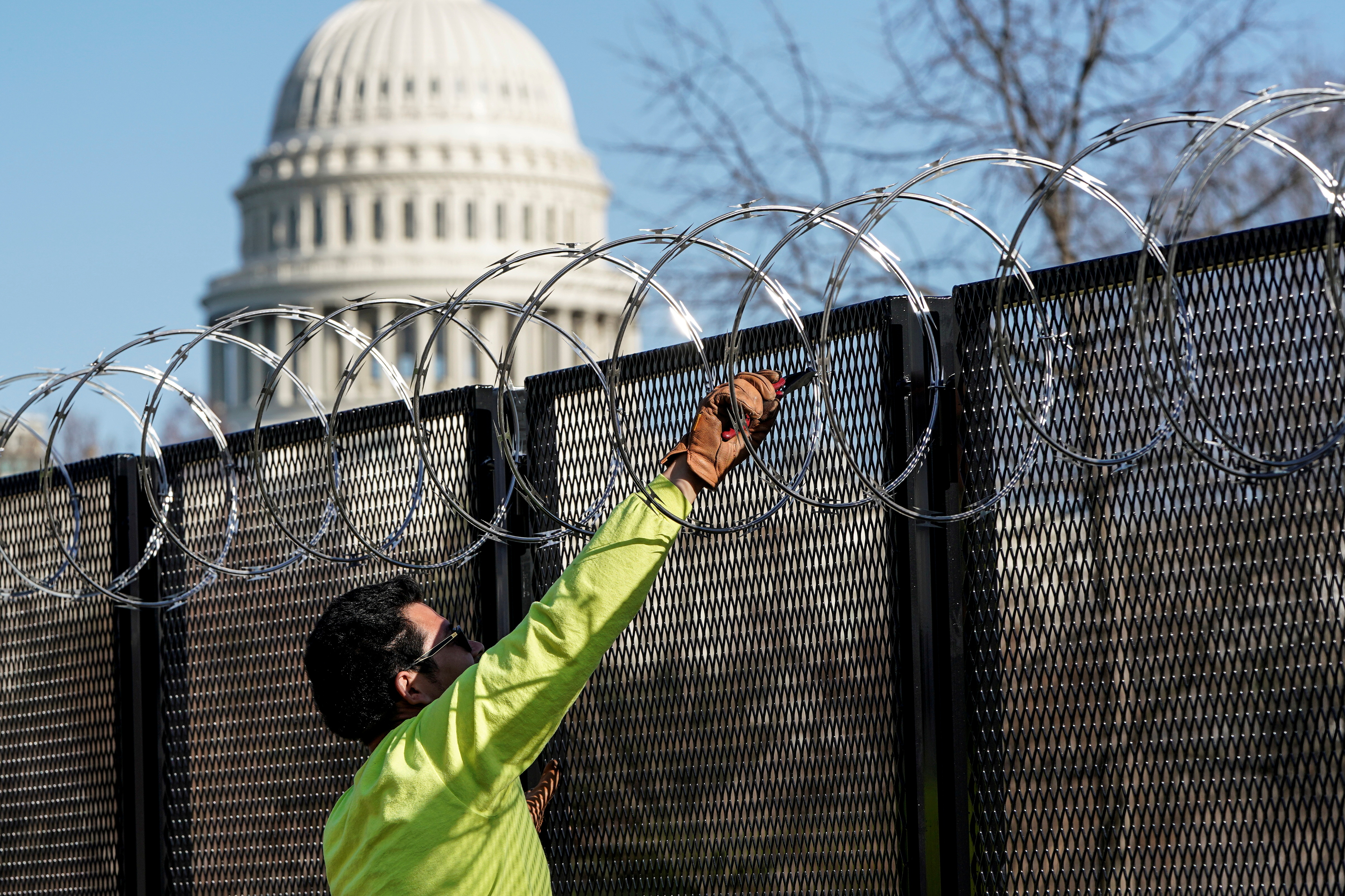 A worker removes razor wire from the top of security fencing as part of a reduction in heightened security measures taken after the January 6th attack on the U.S. Capitol in Washington, U.S., March 20, 2021.      REUTERS/Joshua Roberts/File Photo