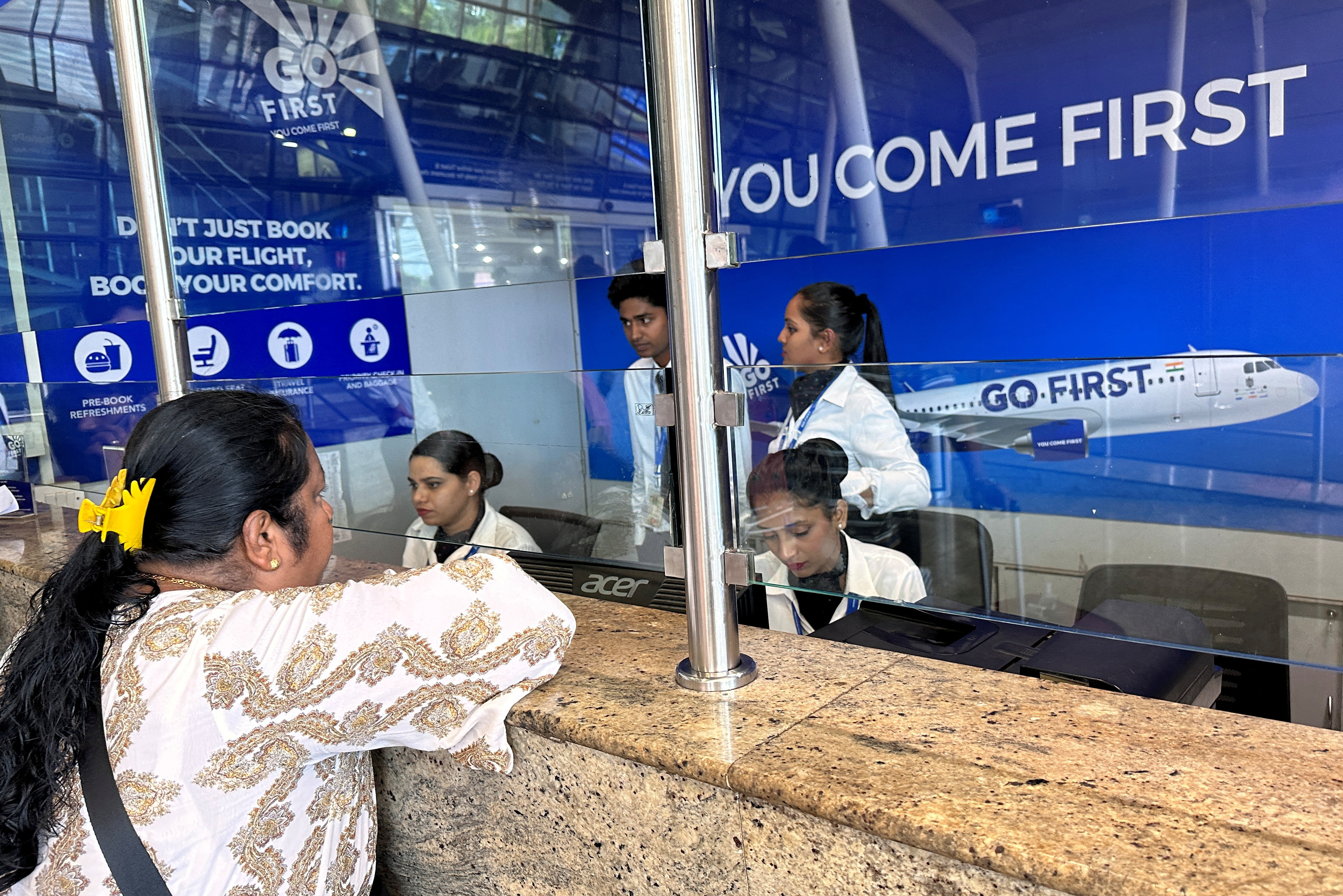A woman speaks to staff at the Go First airline ticketing counter at the Chhatrapati Shivaji International Airport in Mumbai