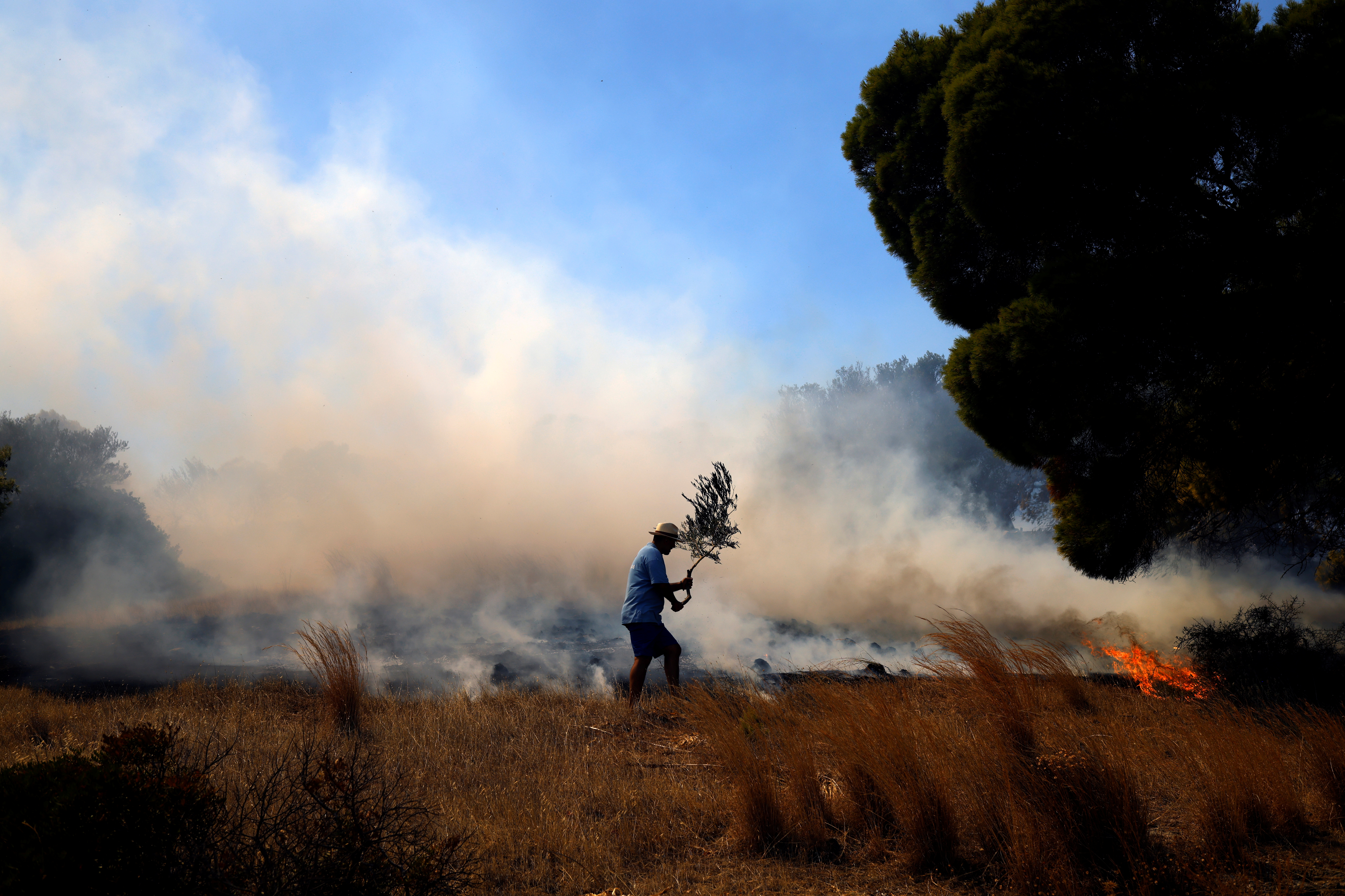 A local tries to extinguish a wildfire burning in the village of Markati, near Athens, Greece, August 16, 2021. REUTERS/Alkis Konstantinidis