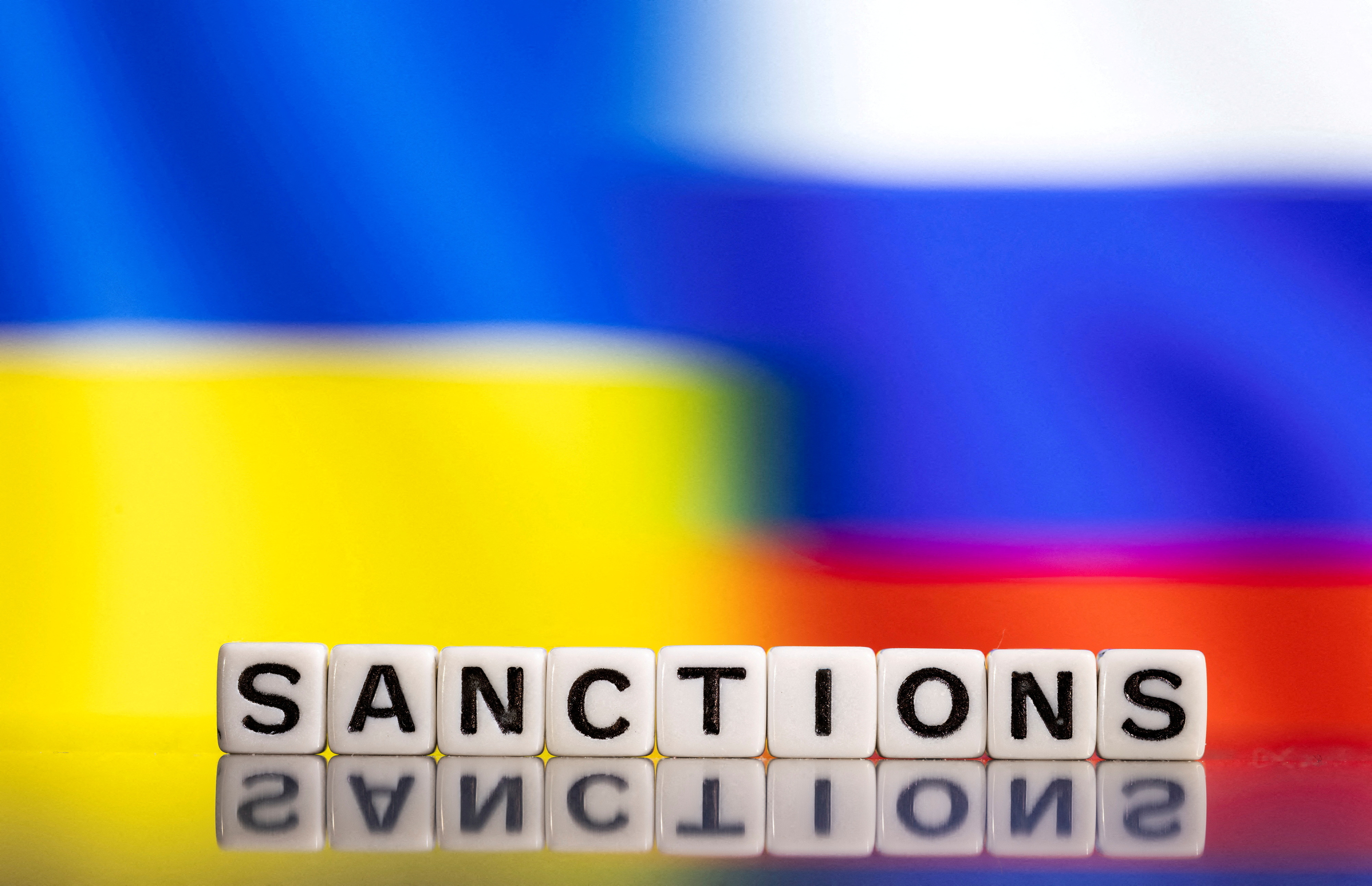 Illustration shows letters arranged to read "Sanctions"  in front of Ukraine's and Russia's flag colors
