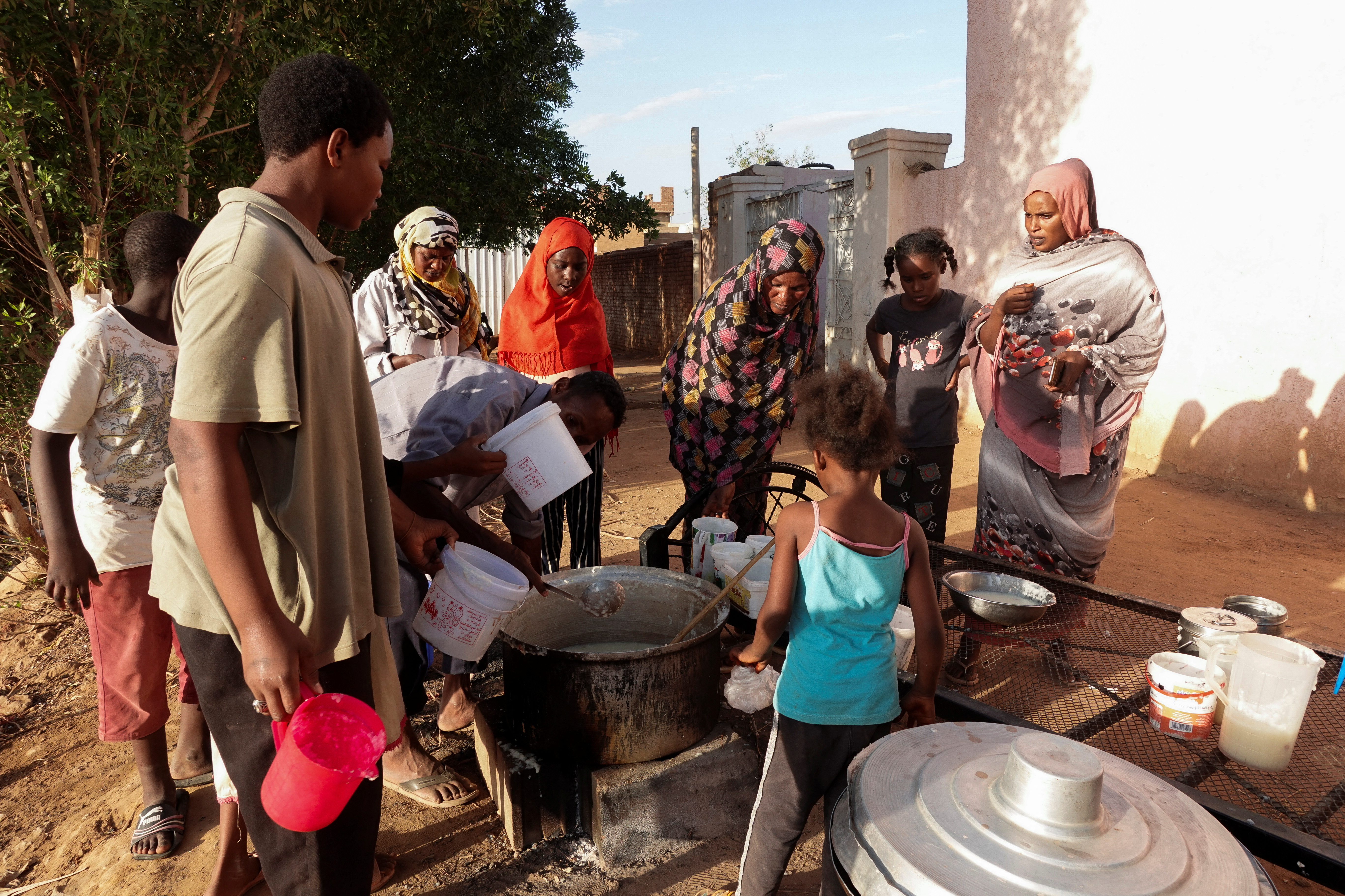Displaced Sudanese families wait to receive food from a charity kitchen, in the city of Omdurman