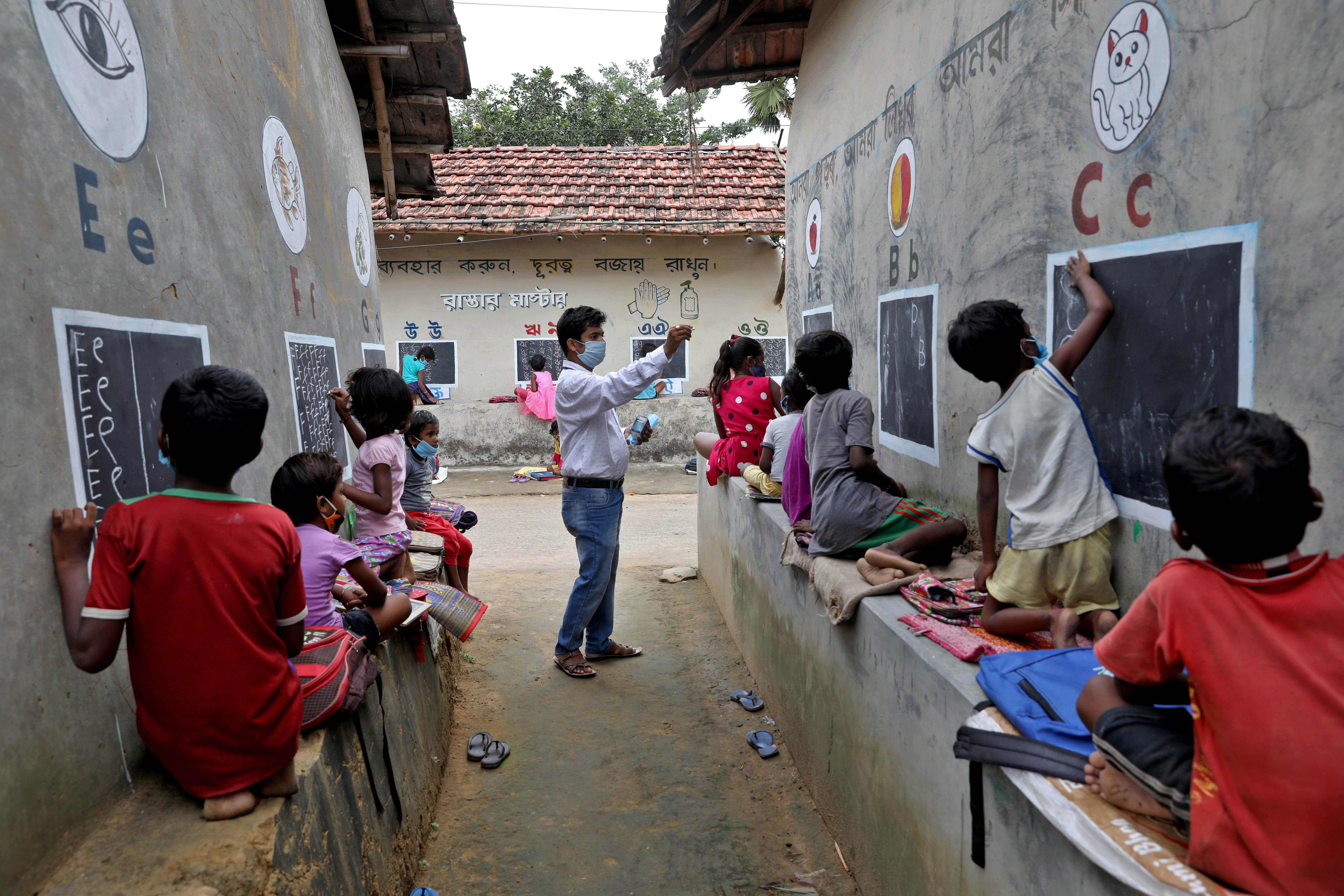 Deep Narayan Nayak teaches children in an open air class outside the houses with the walls converted into black boards at Joba Attpara village
