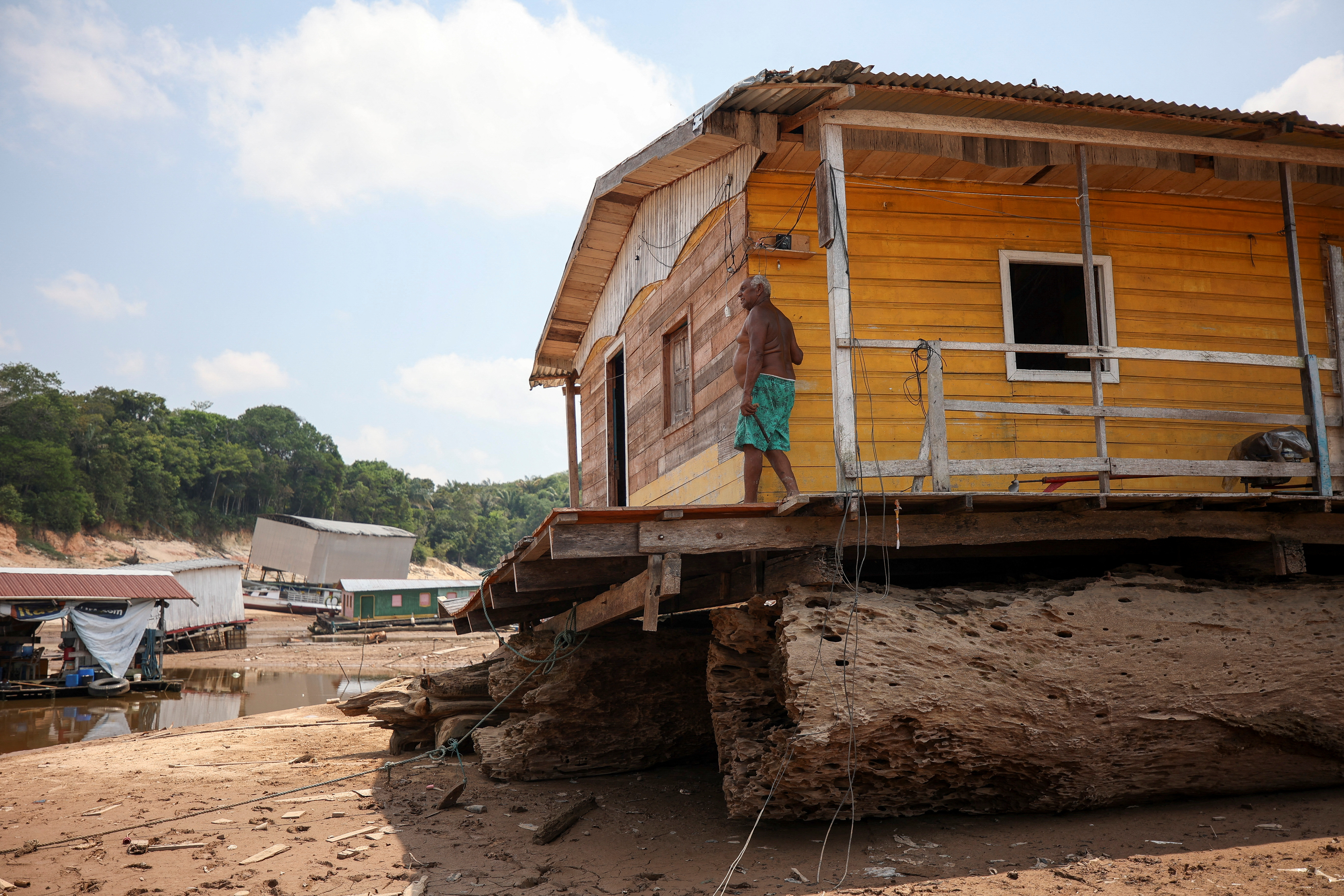 Bernardo da Cunha Reis stands on the porch of his house, which is stranded at David's Marina that has been affected by the drought of the Negro River