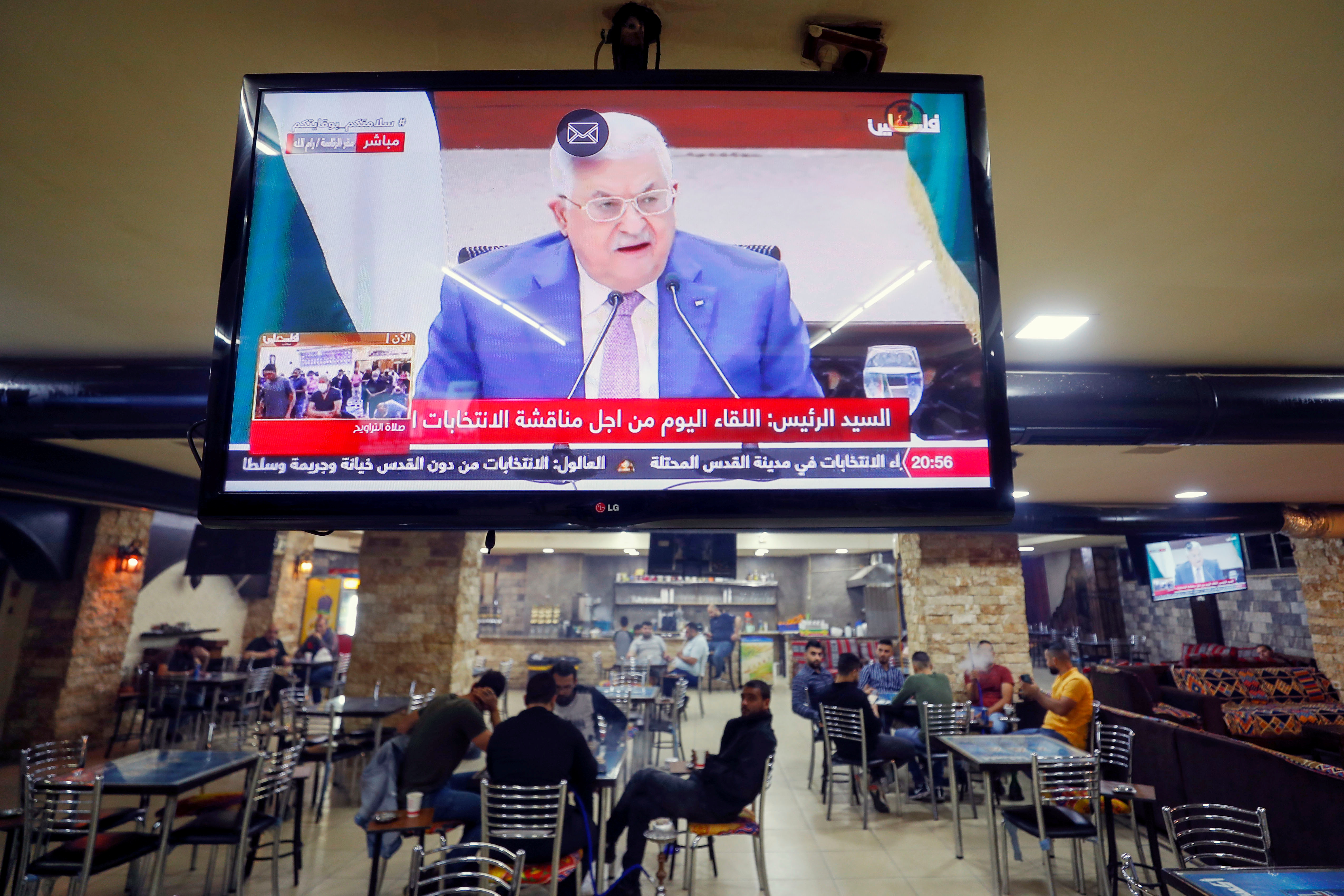 A screen displaying a live broadcast of Palestinian President Mahmoud Abbas's speech during a meeting to discuss upcoming elections, is seen in a coffee shop in Ramallah in the Israeli-occupied West Bank April 29, 2021. REUTERS/Mohamad Torokman