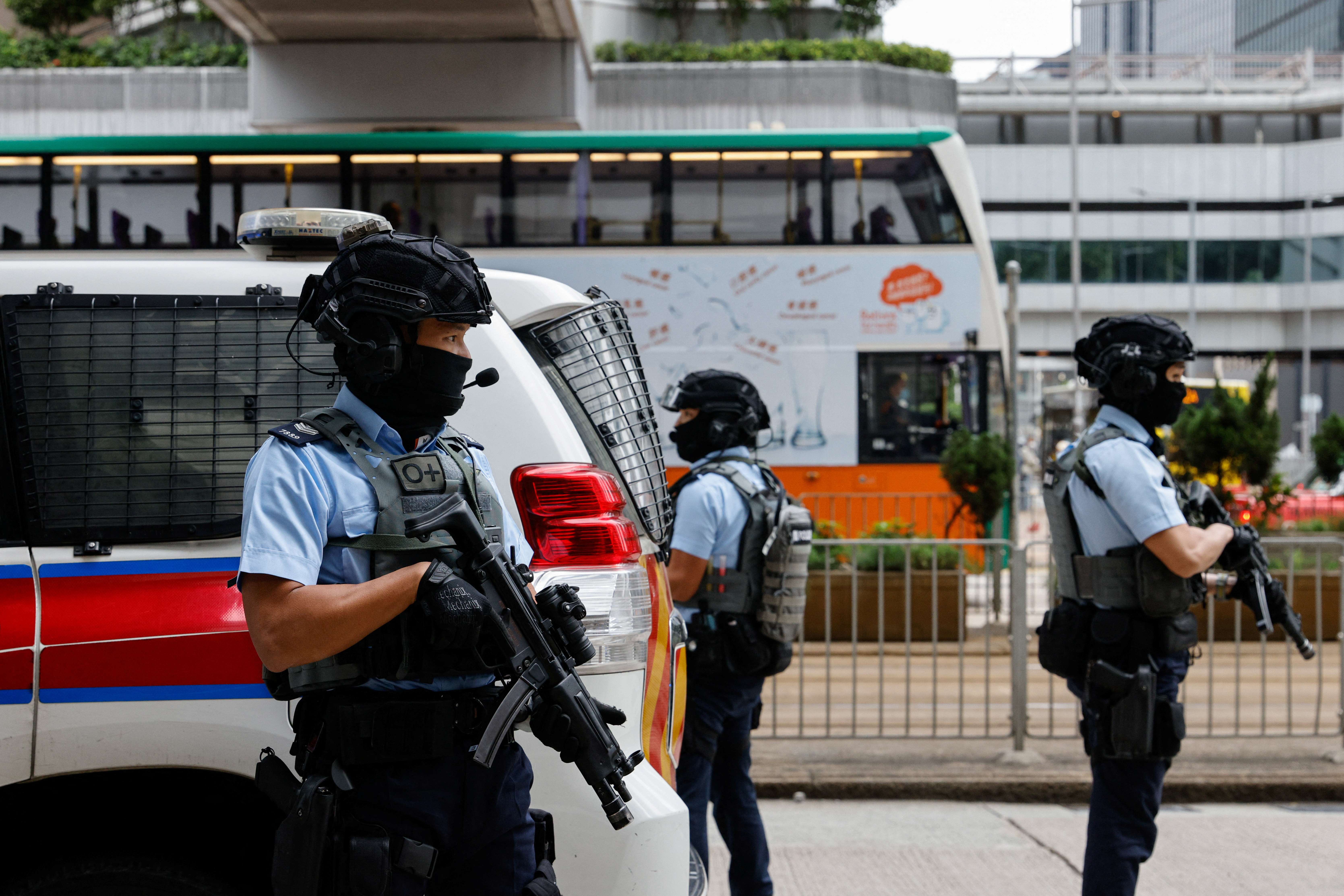 Armed police stand guard as they escort a prison van that is believed to carry media mogul Jimmy Lai, founder of Apple Daily, to the High Court in Hong Kong