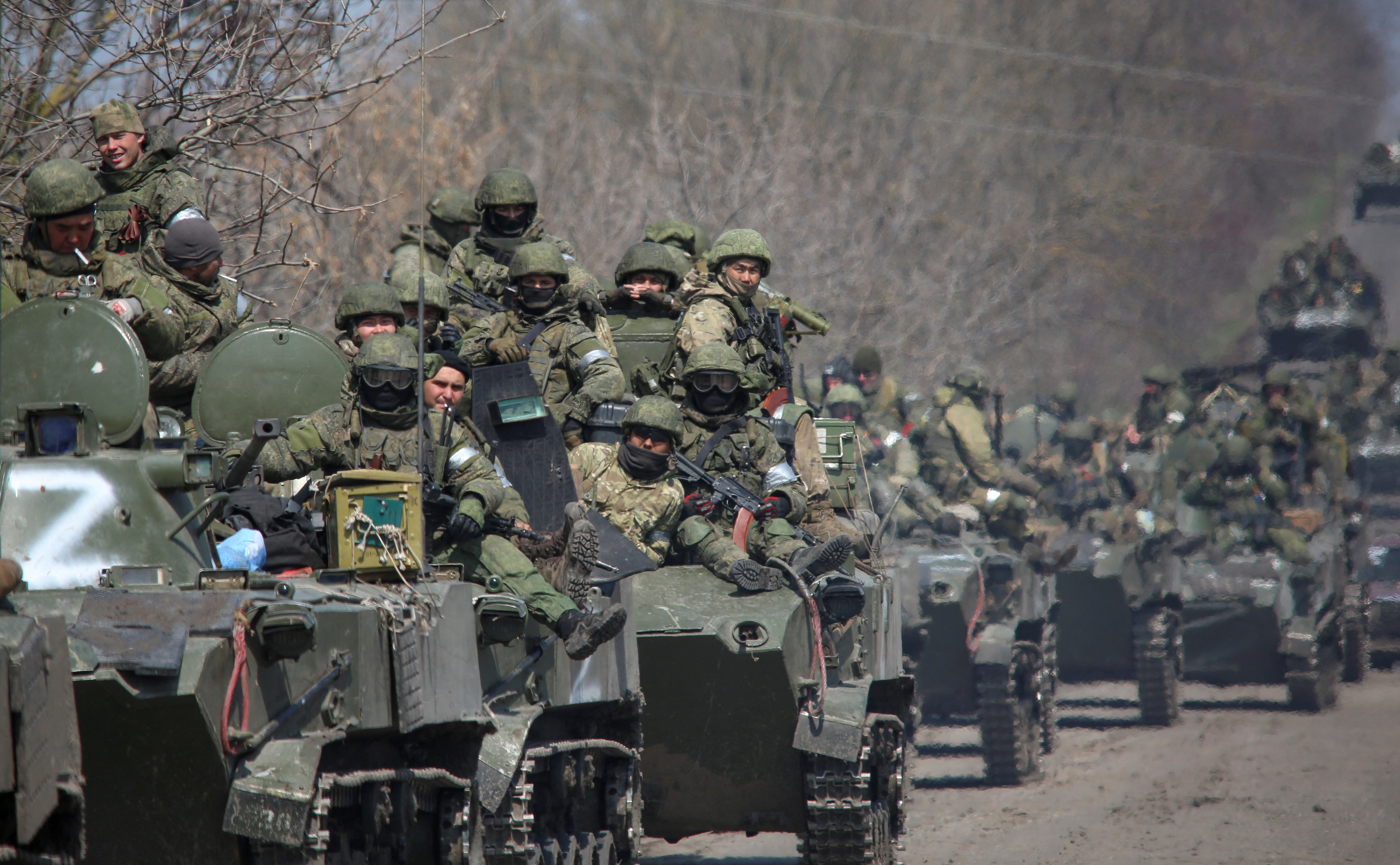Service members of pro-Russian troops ride on armoured vehicles on a road leading to Mariupol