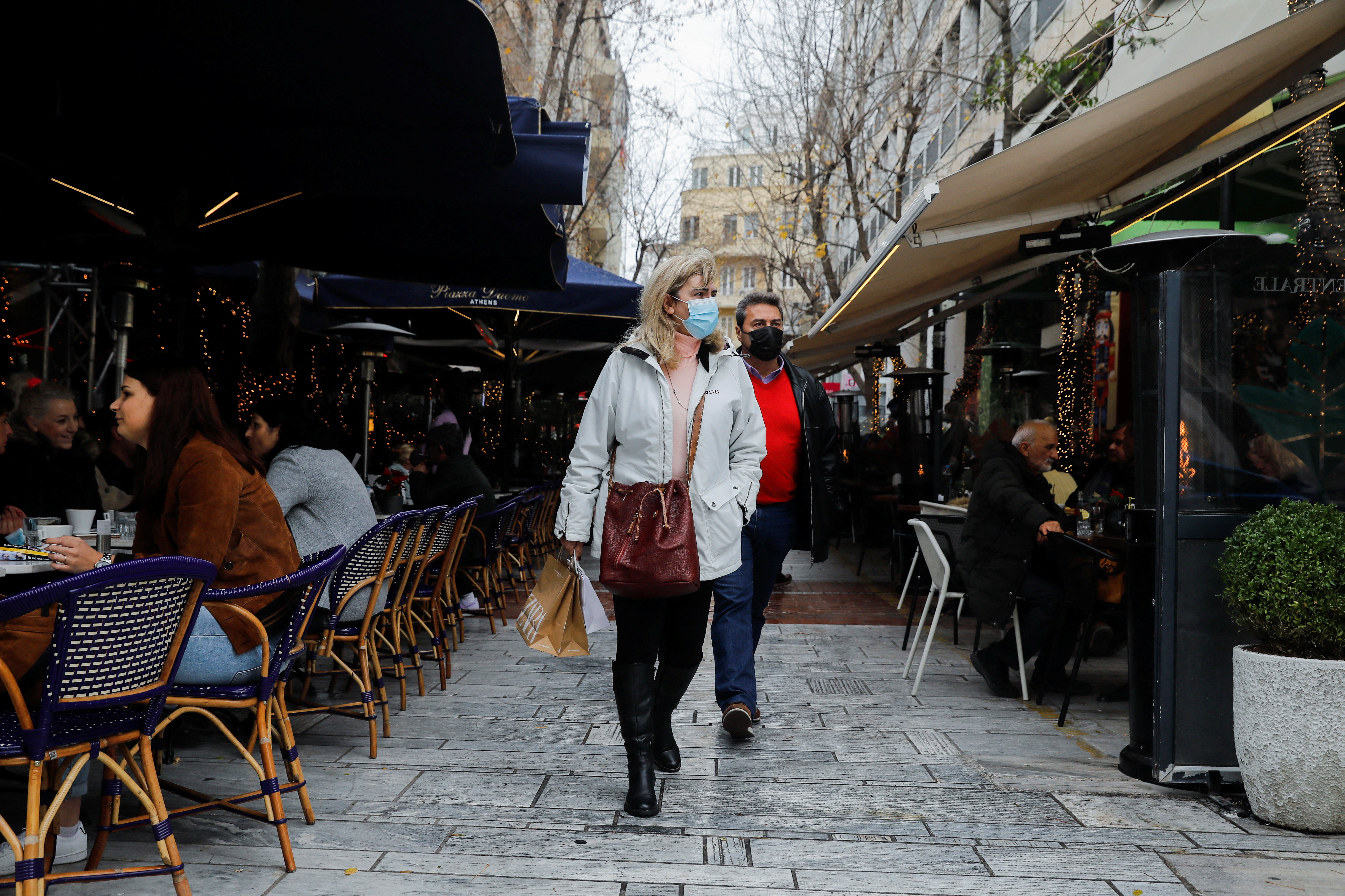 People wearing protective face masks walk past a cafe amid the coronavirus disease (COVID-19) outbreak in Athens