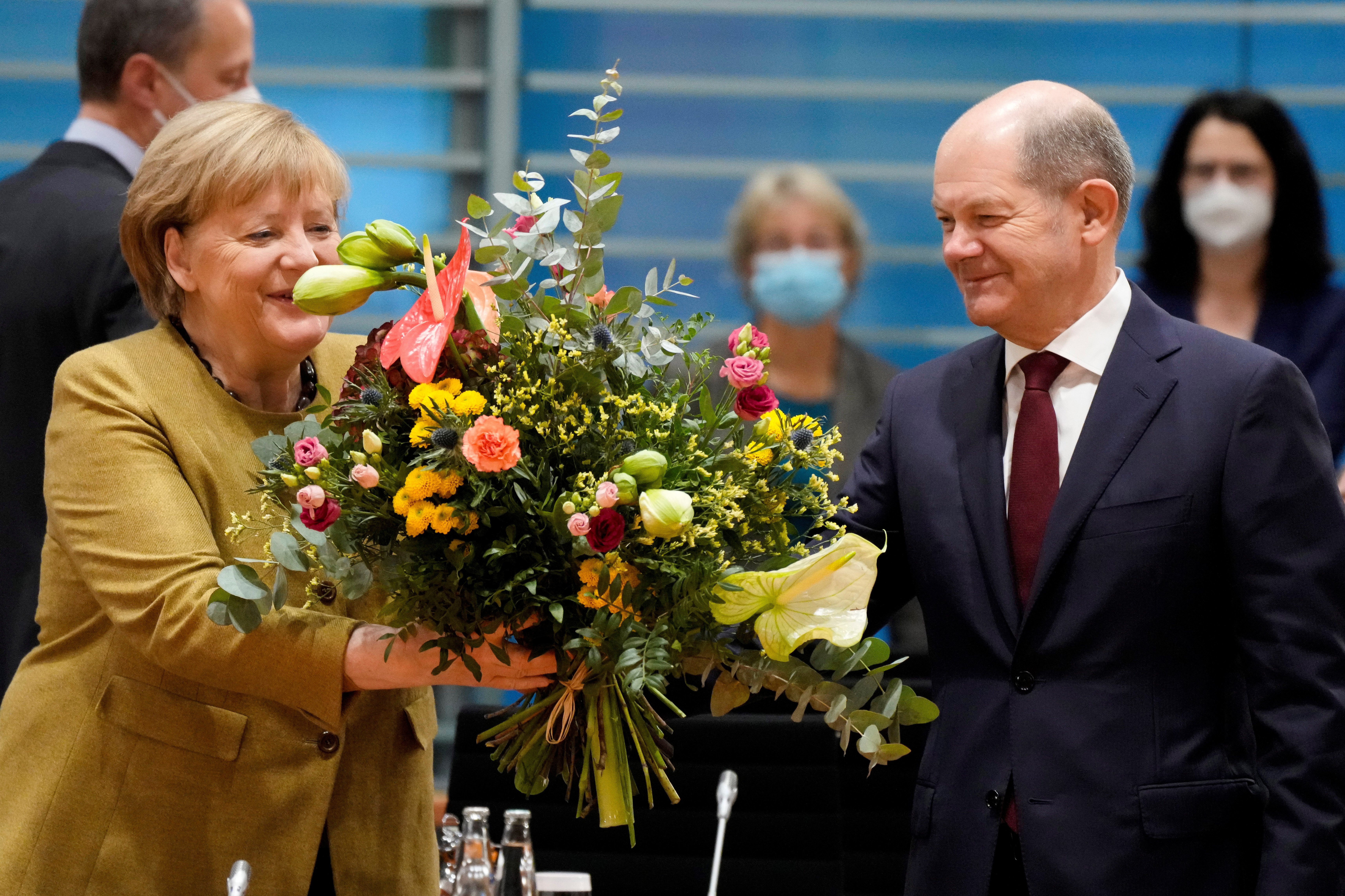 Acting German Chancellor Angela Merkel receives a bouquet from acting German Finance Minister Olaf Scholz prior to the weekly cabinet meeting at the Chancellery in Berlin, Germany, November 24, 2021. Markus Schreiber/Pool via REUTERS