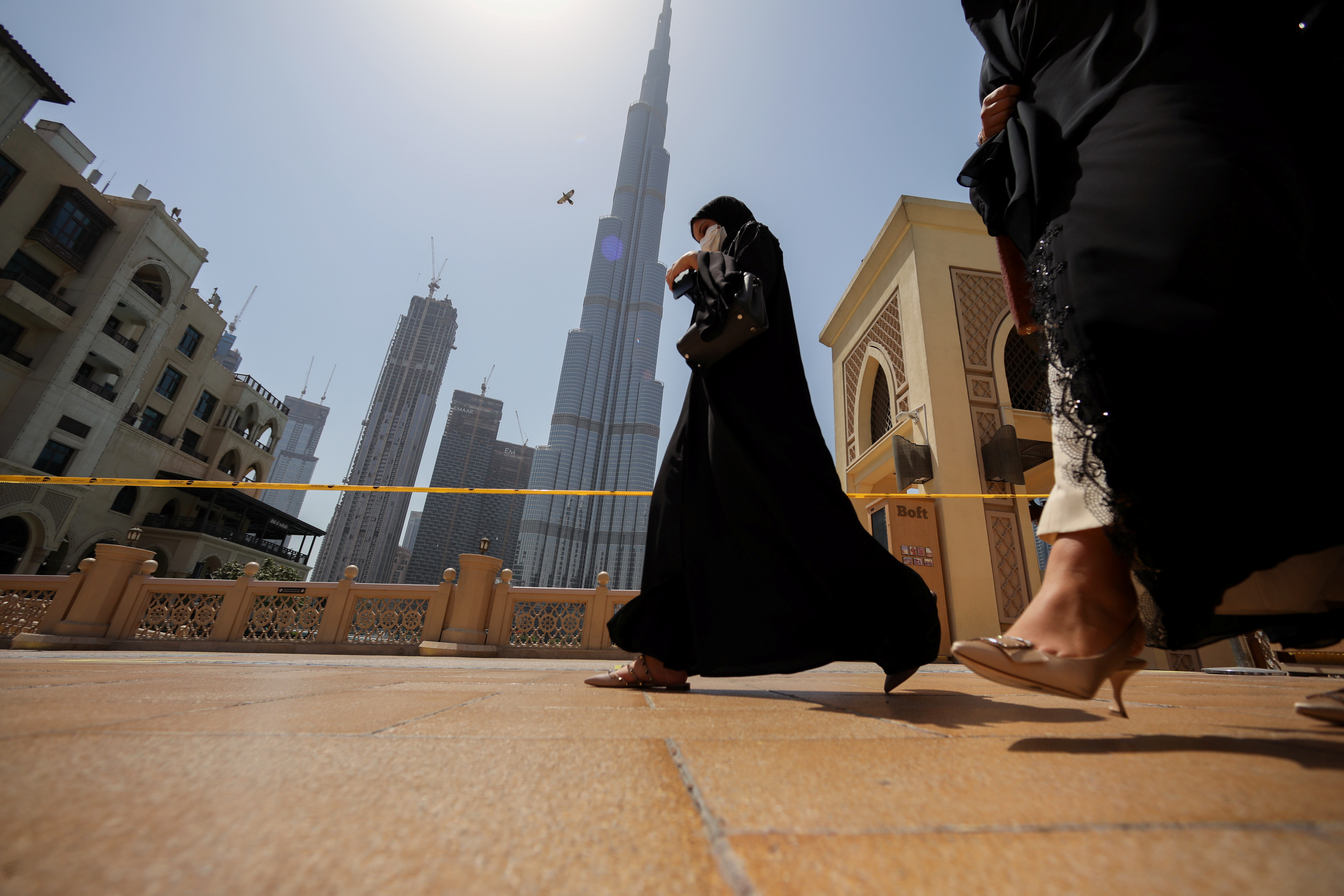 Women walk past the Burj Khalifa in Dubai