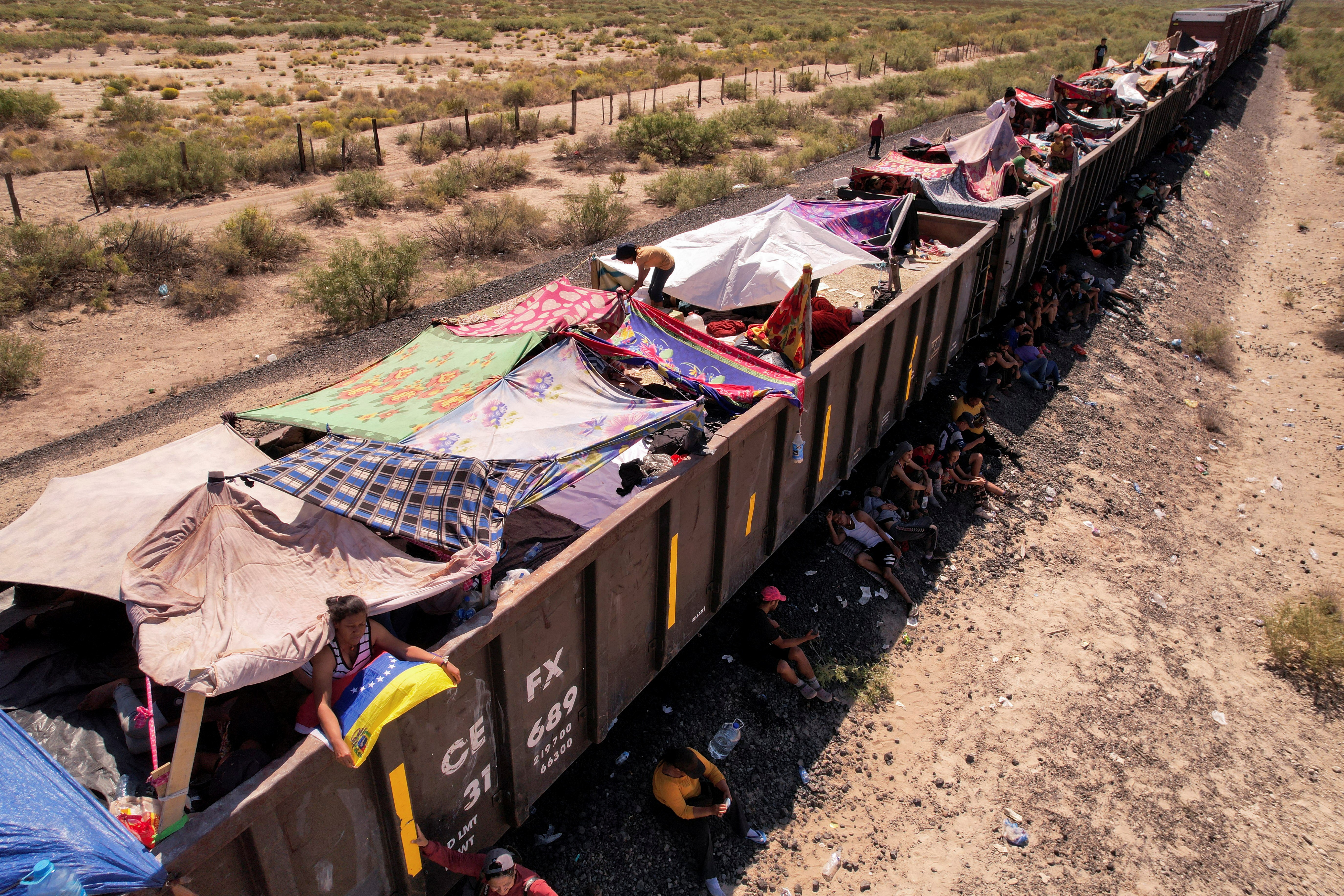 Migrants travelling by train to Ciudad Juarez wait near train wagons while being stranded near Villa Ahumada