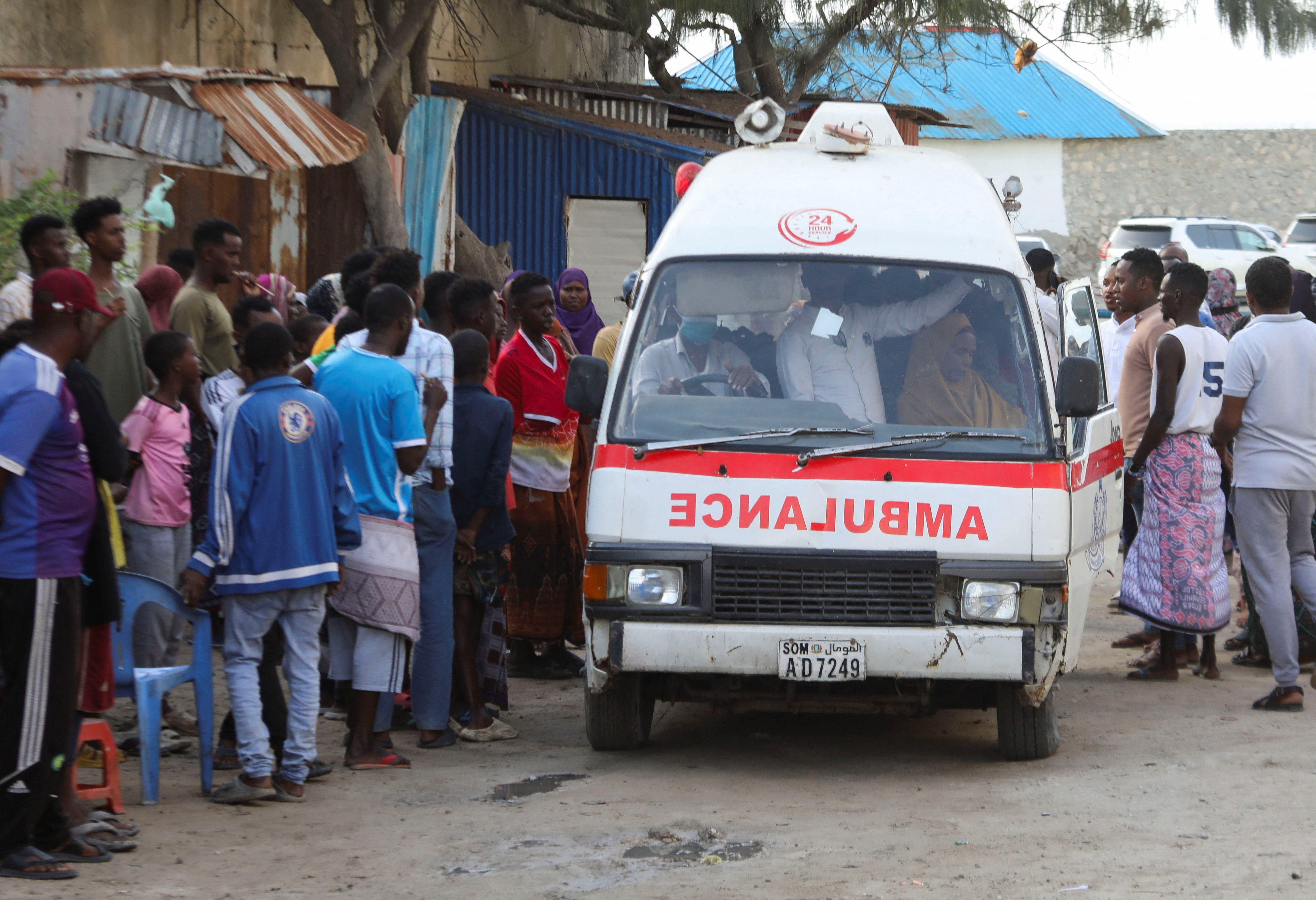 People gather as an ambulance carries the dead body of an unidentified woman killed in an explosion that occurred while revellers were swimming at the Lido beach in Mogadishu