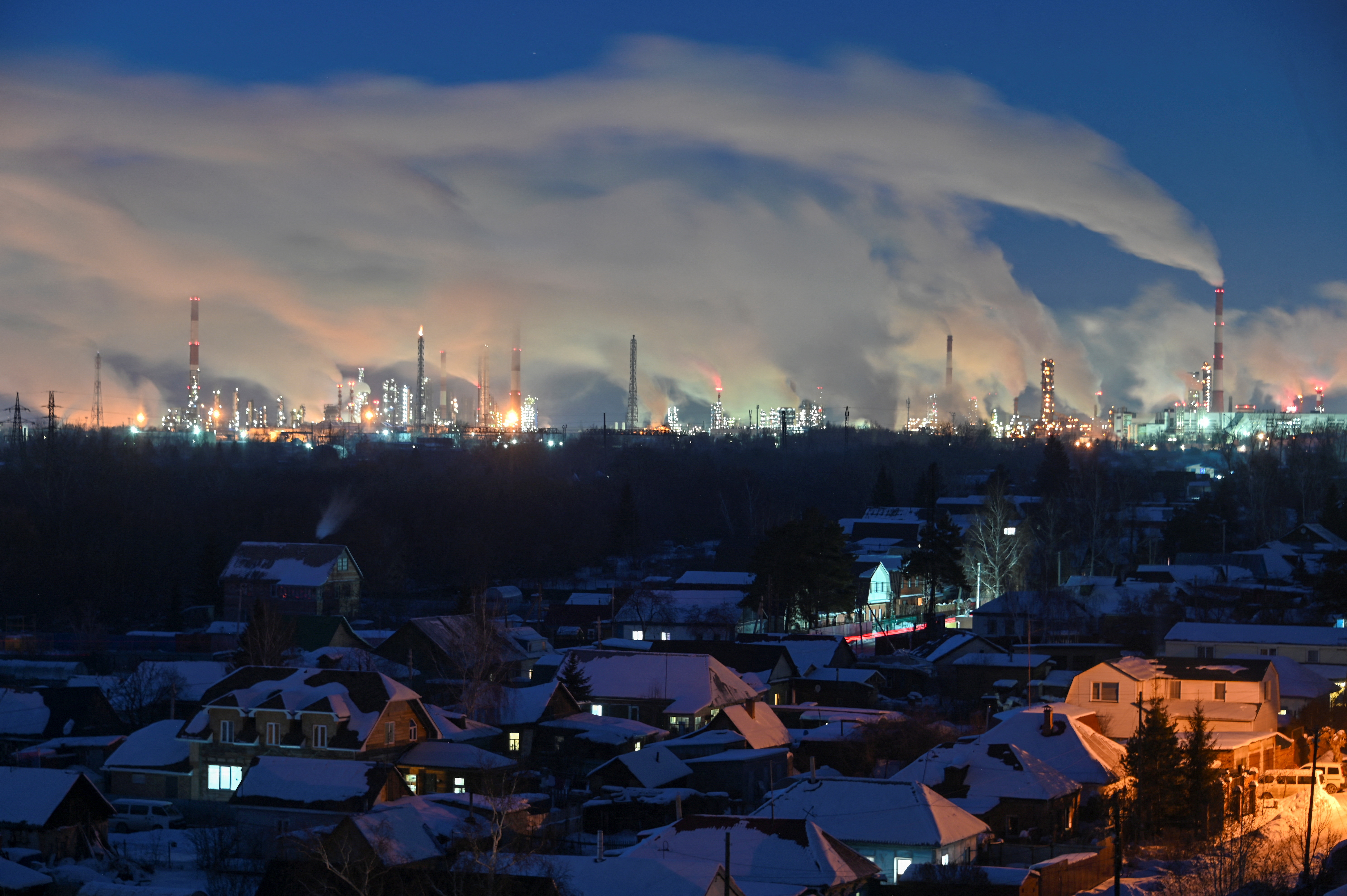 Flue gas and steam rise out of chimneys of an oil refinery in Omsk