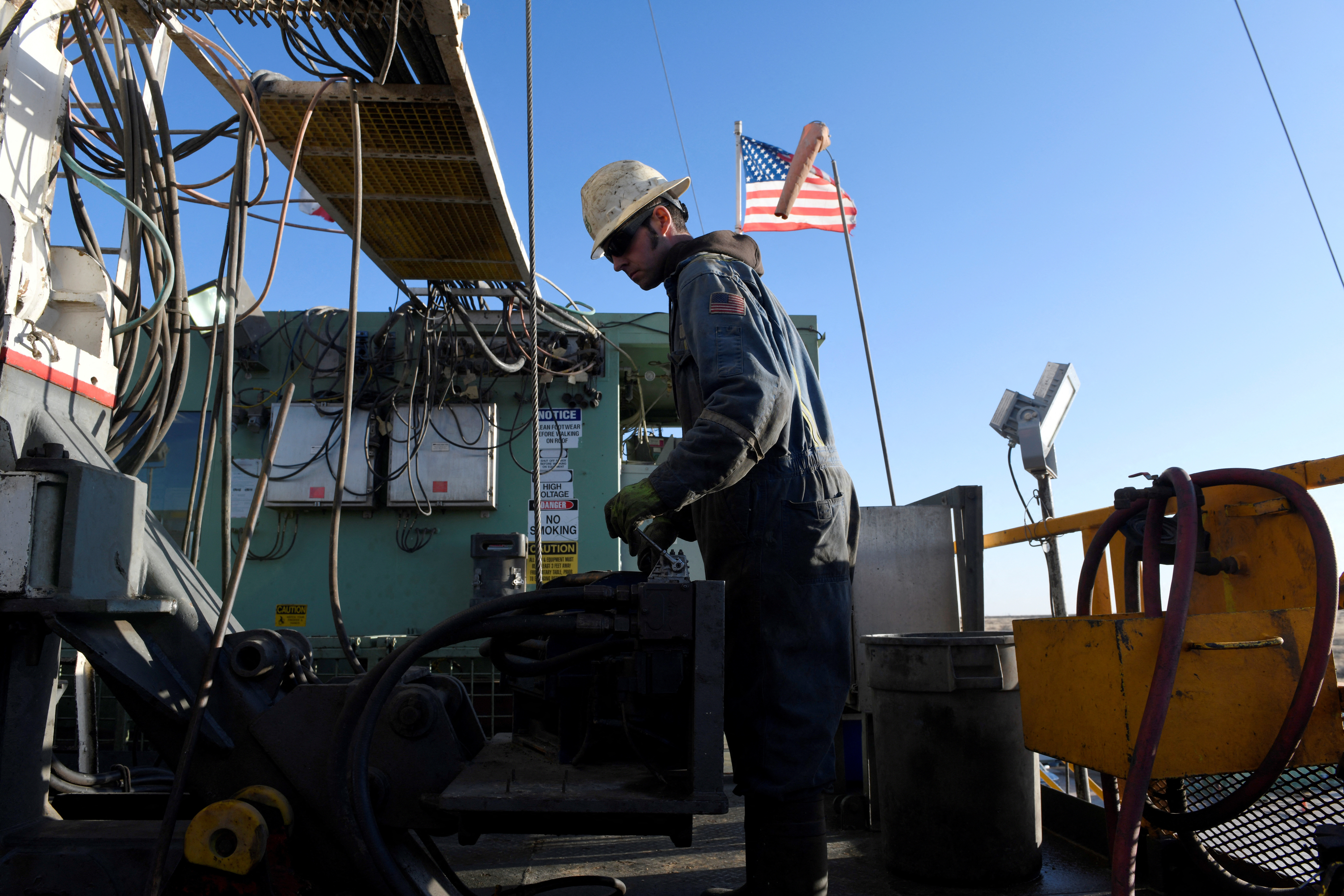 A worker operates equipment on a drilling rig near Midland