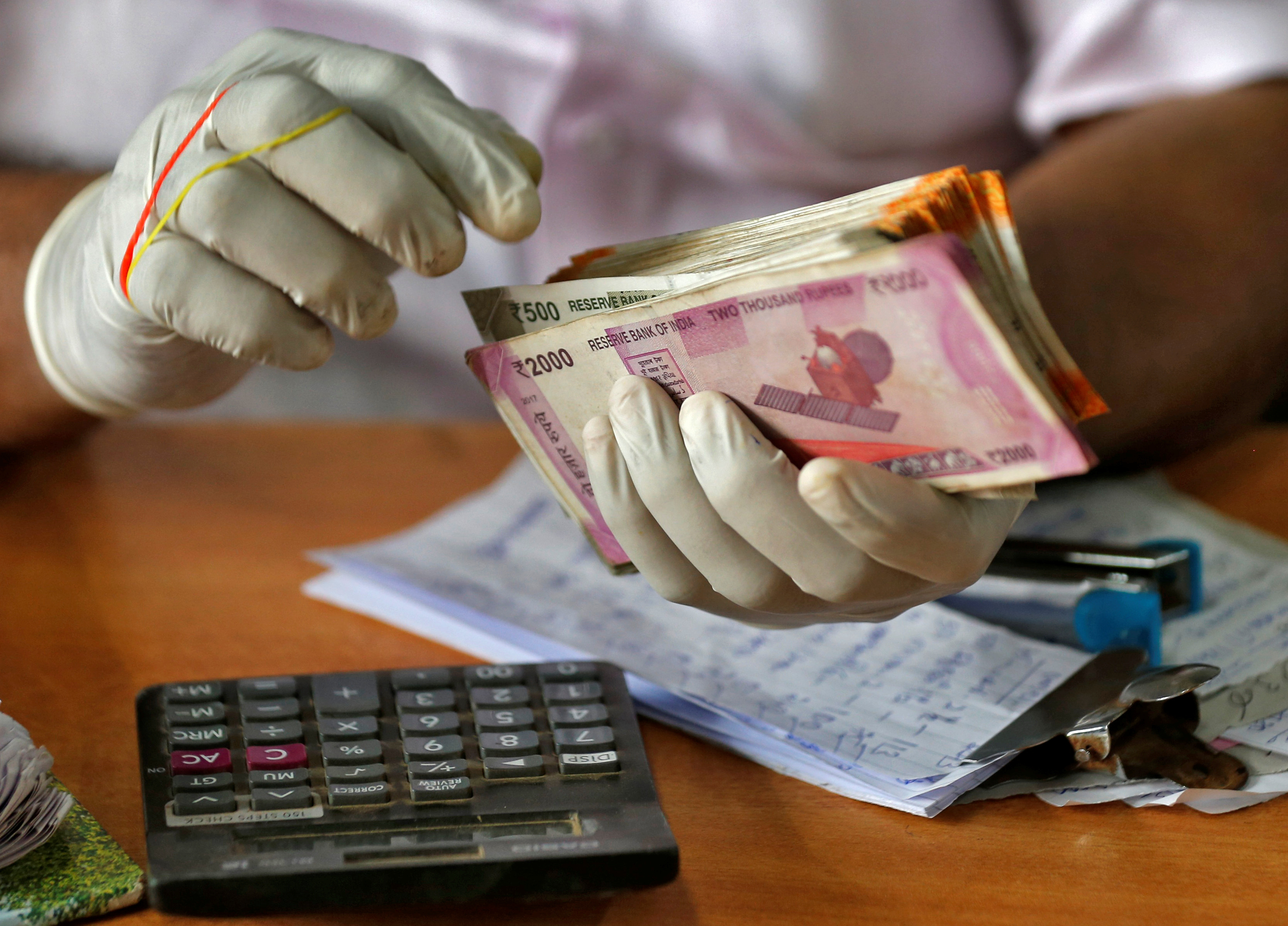 A trader wearing protective hand gloves count Indian currency notes at a market during a 21-day nationwide lockdown to limit the spreading of coronavirus disease (COVID-19) in Kochi