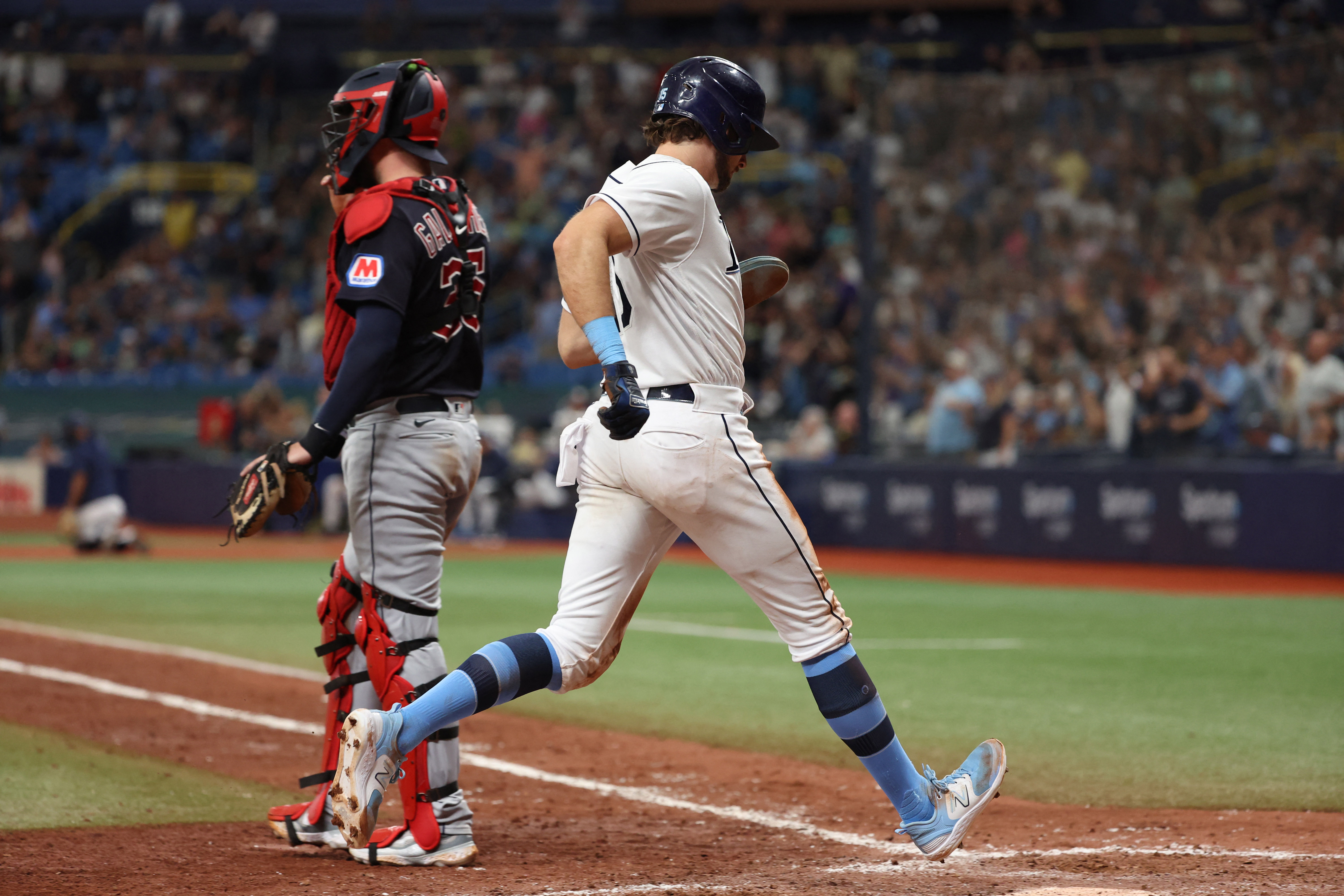 Tampa Bay Rays' Randy Arozarena is congratulated by teammates after scoring  the in the ninth inning of a baseball game against the Cleveland Indians,  Friday, July 23, 2021, in Cleveland. (AP Photo/Tony