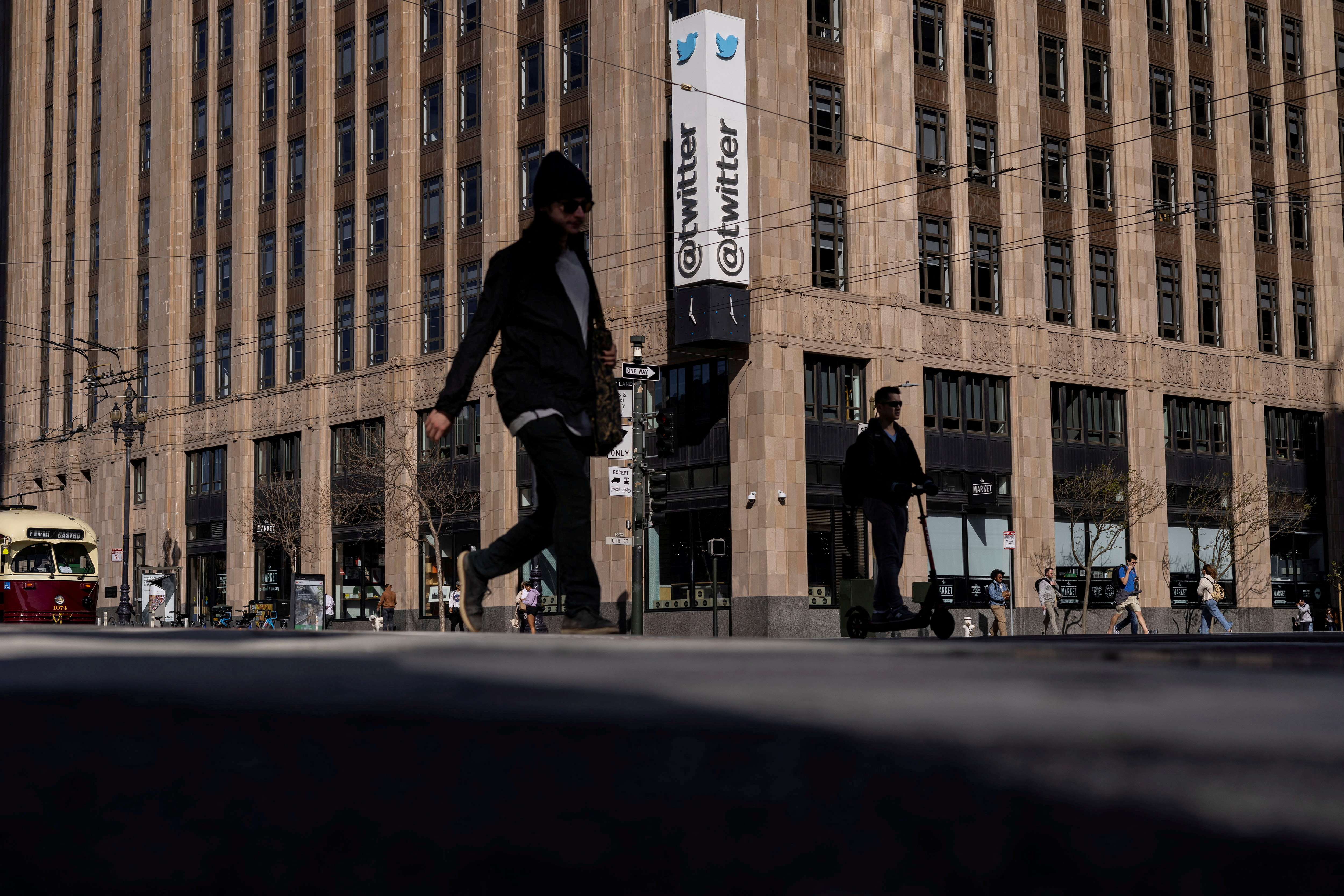 People walk by a Twitter logo at the company headquarters in downtown San Francisco, California