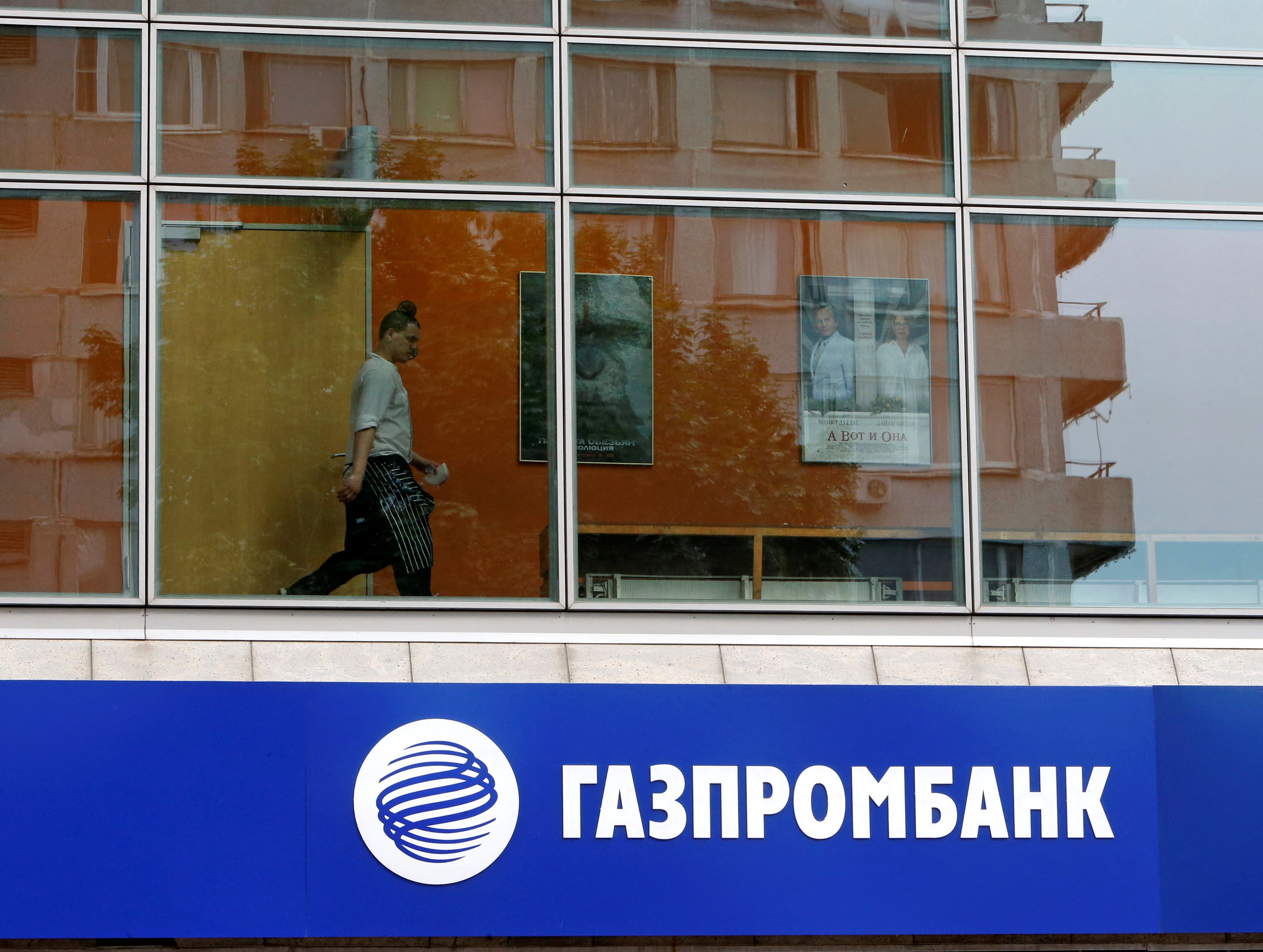 A person is pictured through a window above a Gazprombank branch in Moscow