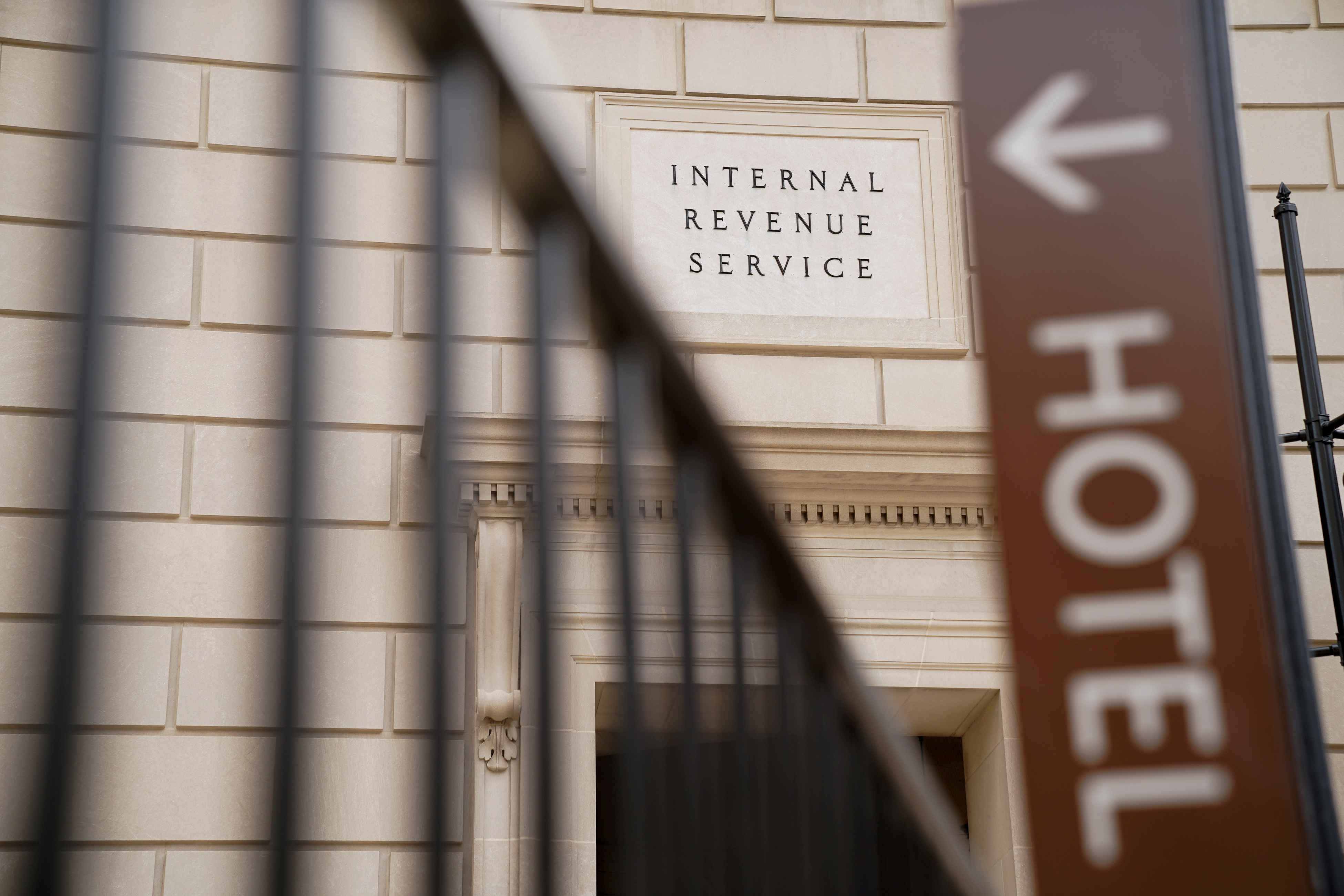 The Internal Revenue Service building is seen behind a sign for the Trump International Hotel