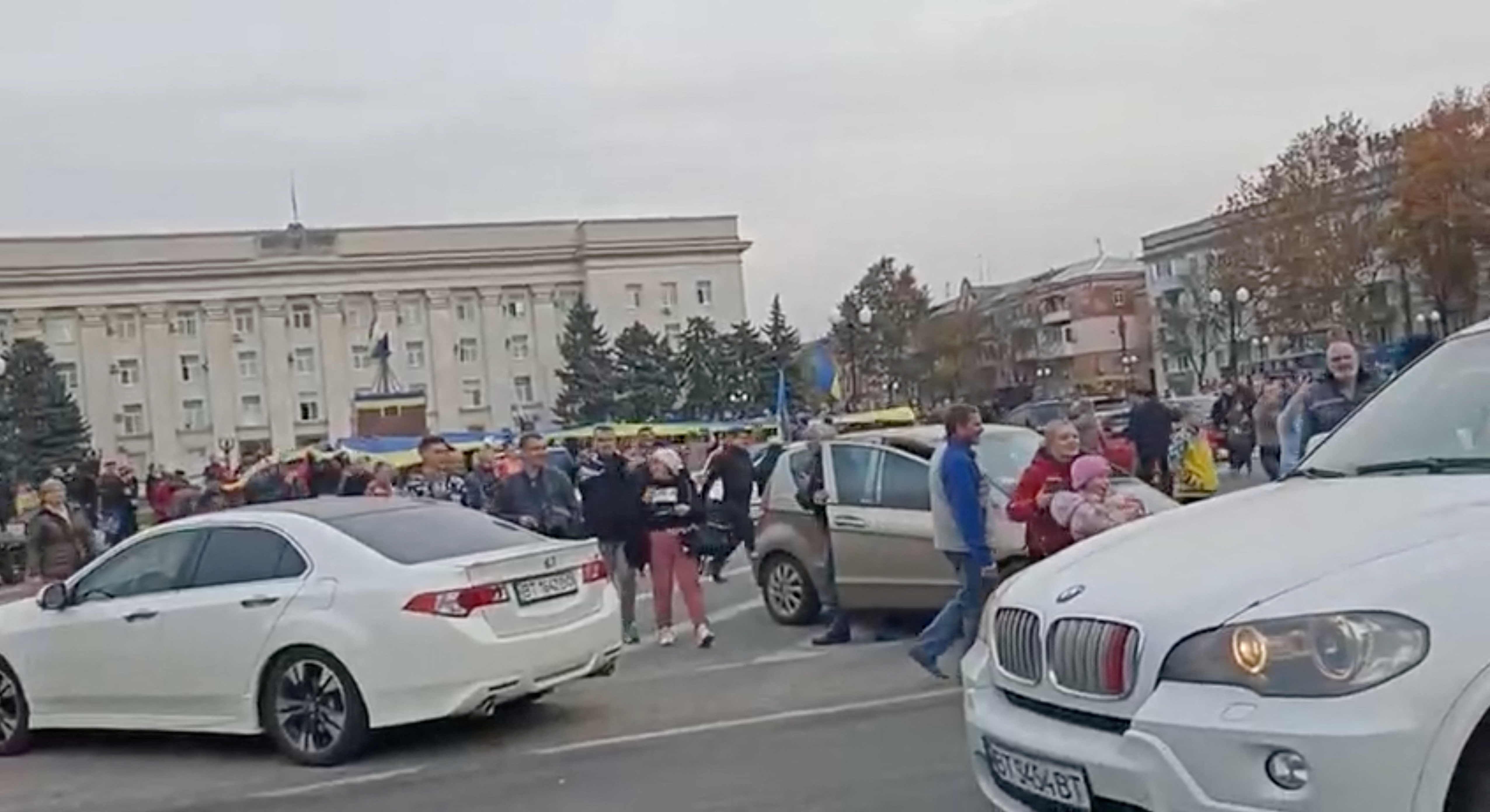 Crowd cheer and chant as they surround a car with Ukrainian soldiers in Kherson Freedom Square