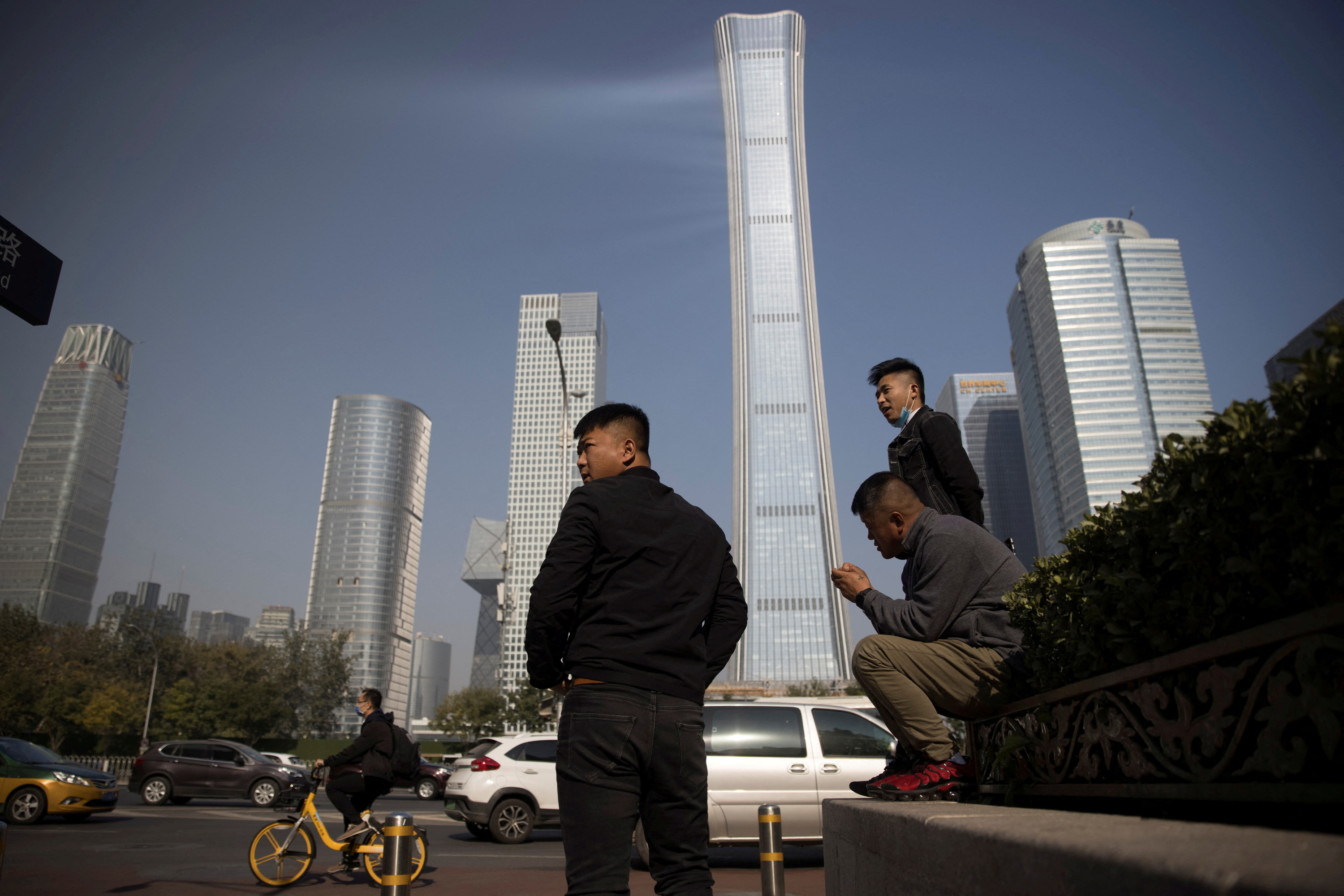 People wait near the skyline of the Central Business District in Beijing