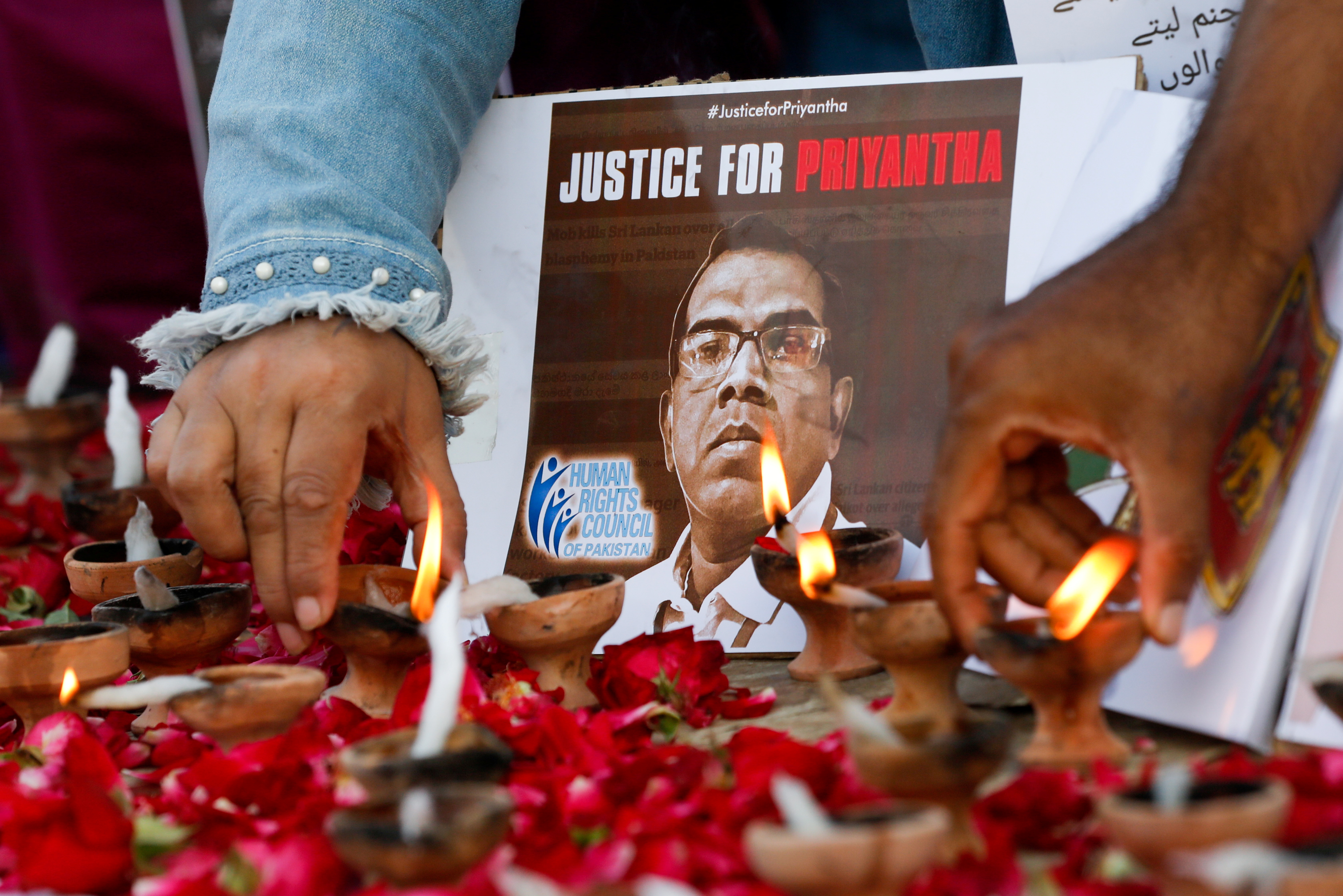 People light oil lamps next to laid roses to express their condolences to the people of Sri Lanka, following the lynching of the Sri Lankan manager of a garment factory after an attack on the factory in Sialkot, in Karachi, Pakistan December 5, 2021. REUTERS/Akhtar Soomro