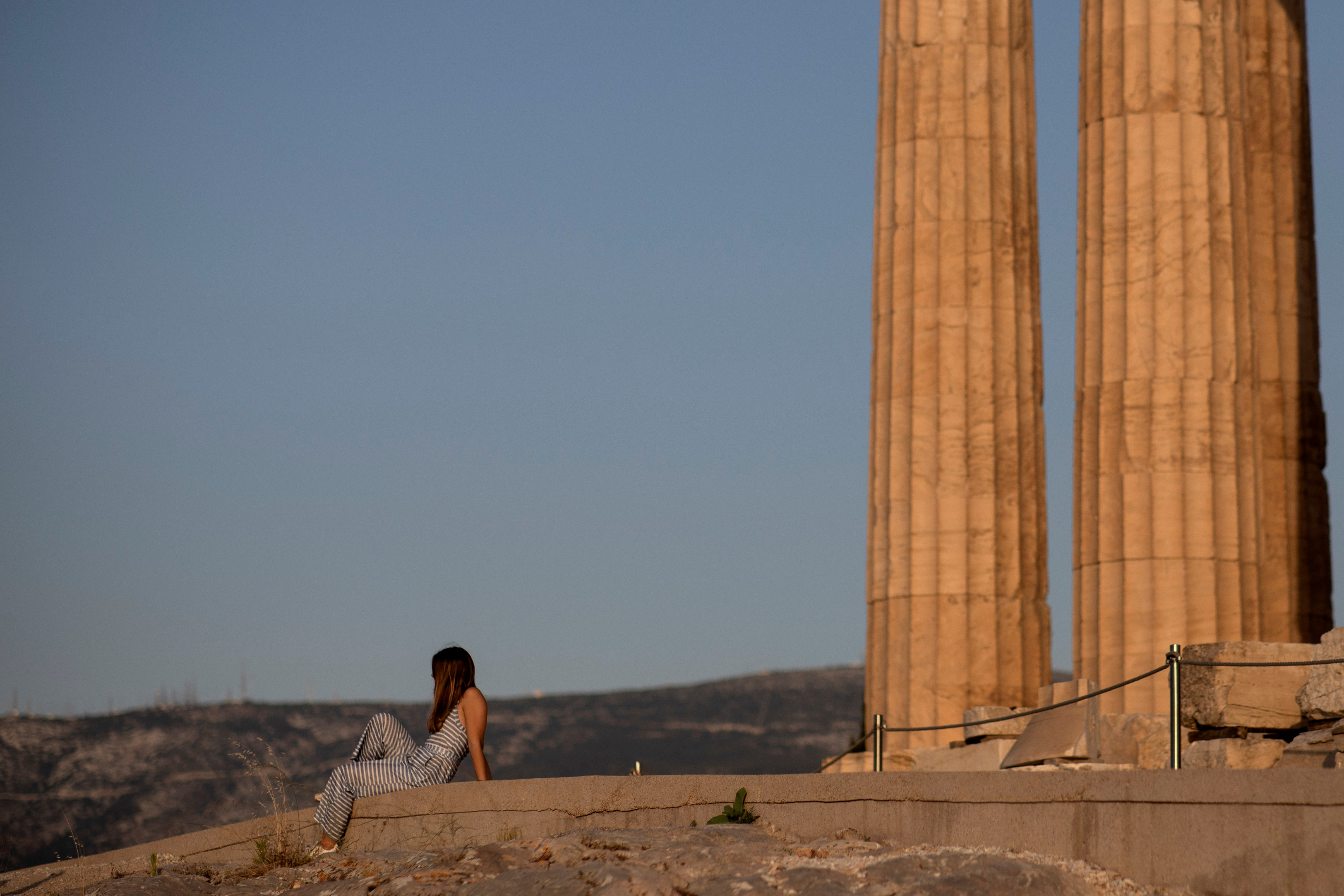 A woman rests on a new cement walkway next to the Parthenon temple, built to improve access for people with disabilities atop the Acropolis hill, in Athens