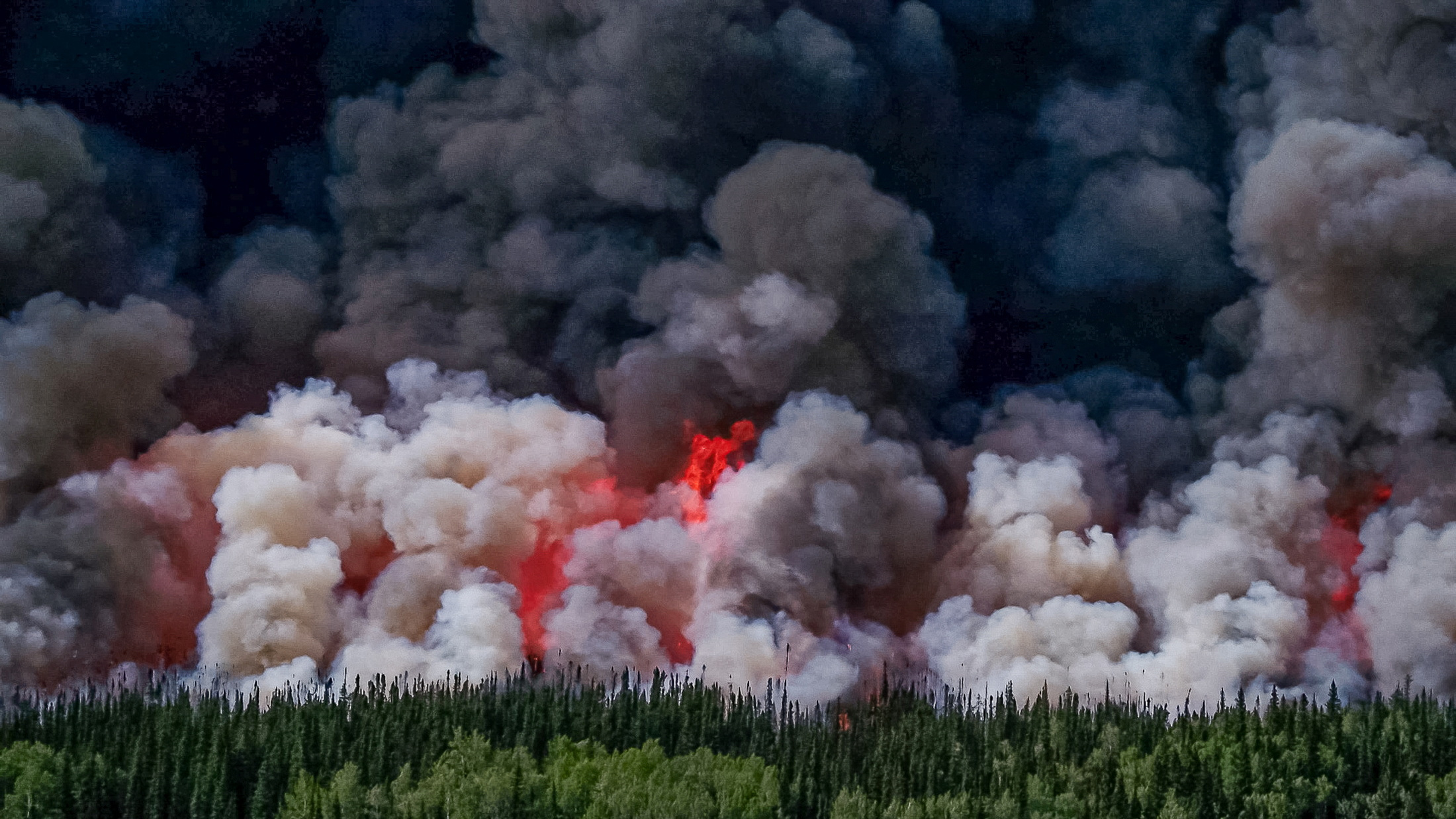 Smoke billows upwards from a planned ignition by firefighters tackling the Donnie Creek Complex wildfire south of Fort Nelson