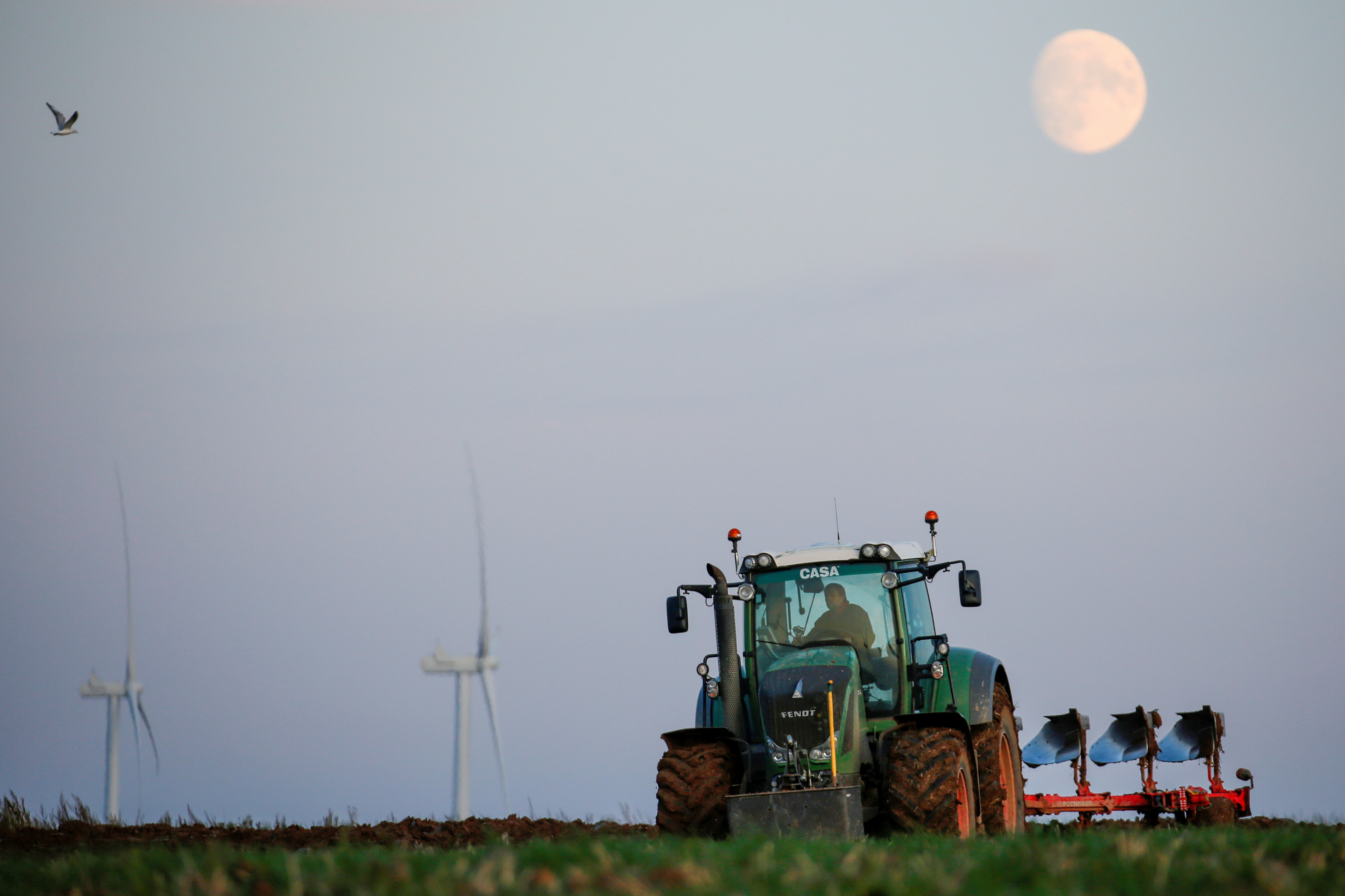 Un granjero ara su campo mientras aparece la luna en Havrincourt