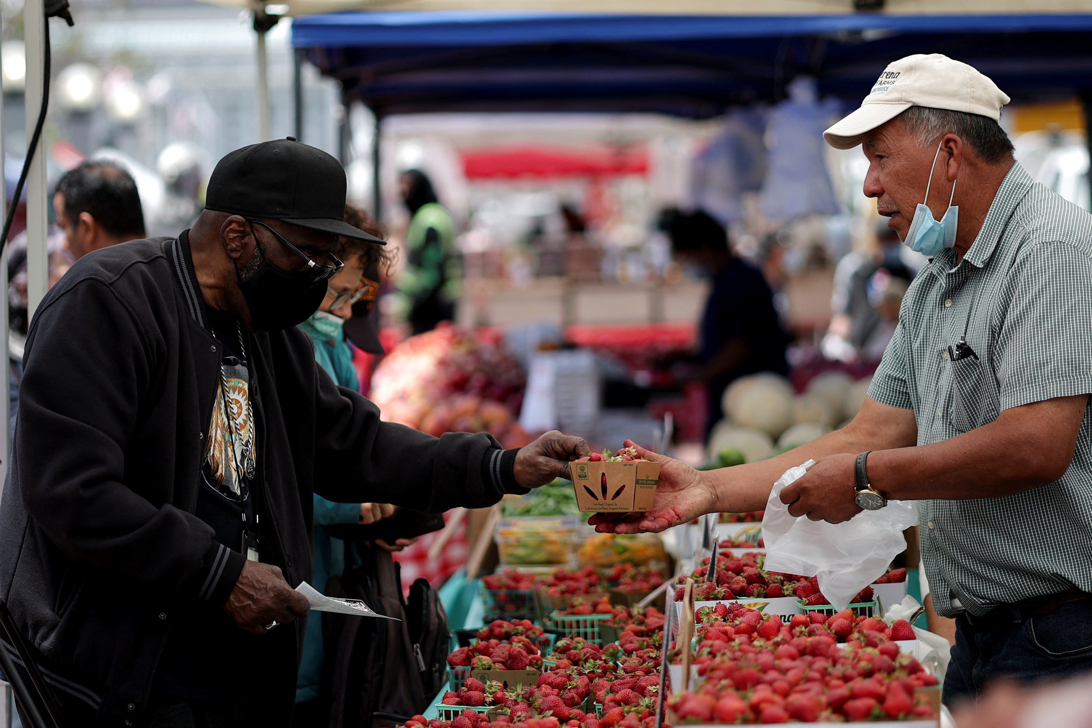 एक निवासी सैन फ्रांसिस्को, कैलिफोर्निया में एक स्थानीय बाजार में स्ट्रॉबेरी खरीदता है
