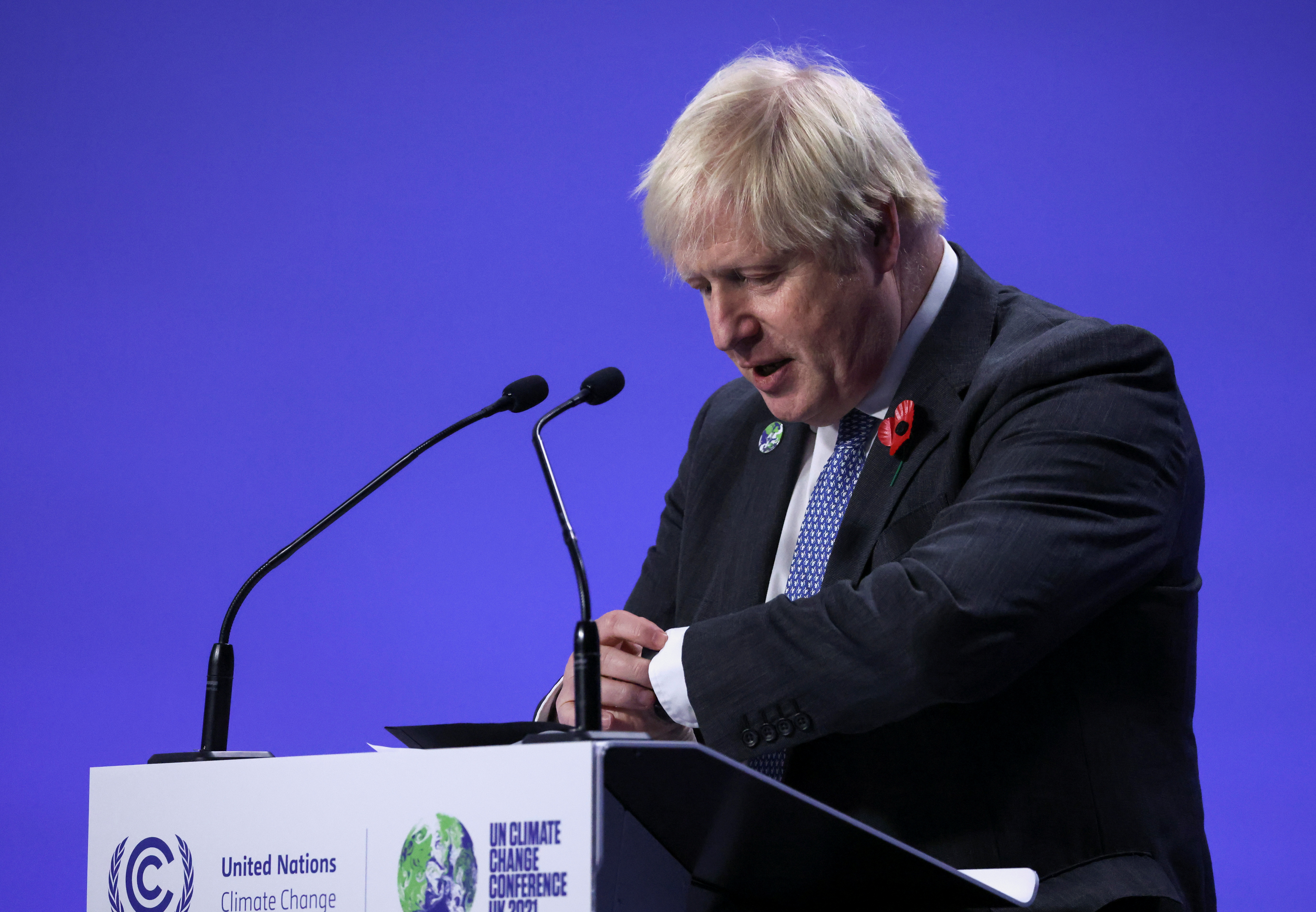 Britain's Prime Minister Boris Johnson looks at his watch while he holds a news conference during the UN Climate Change Conference (COP26) in Glasgow, Scotland, Britain, November 10, 2021. REUTERS/Yves Herman